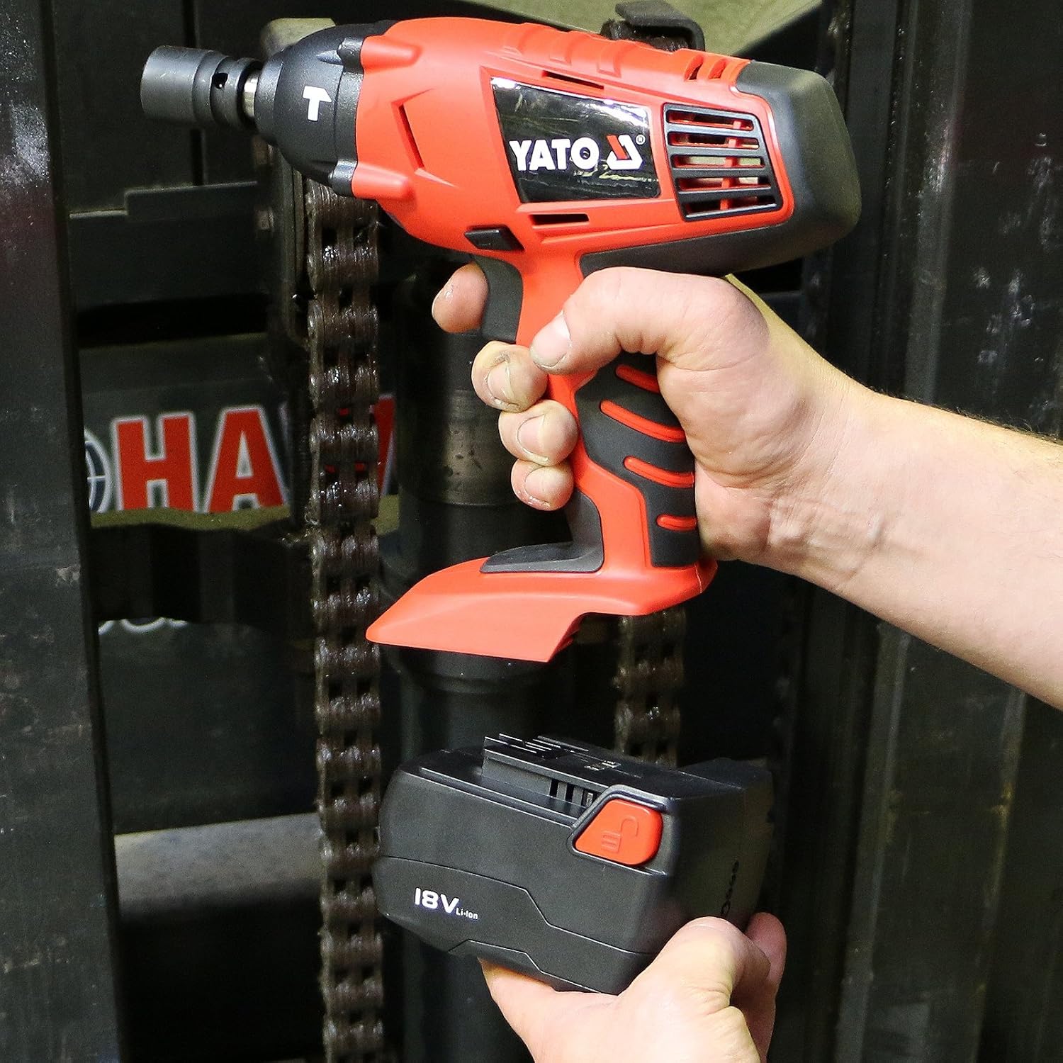 Hands installing a Yato 18V battery into the base of the impact wrench