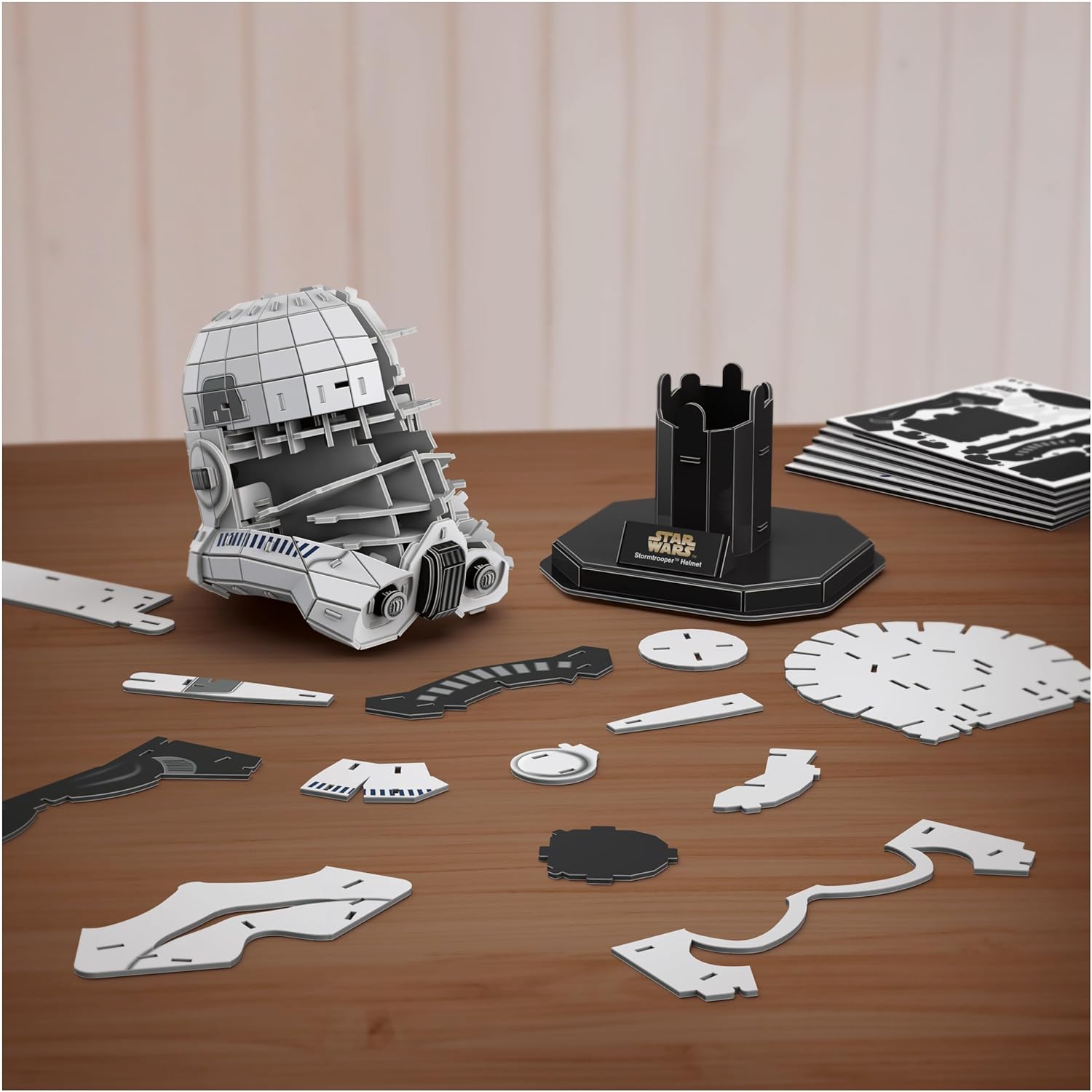 Hands carefully assembling the cardstock pieces of the Stormtrooper helmet model.