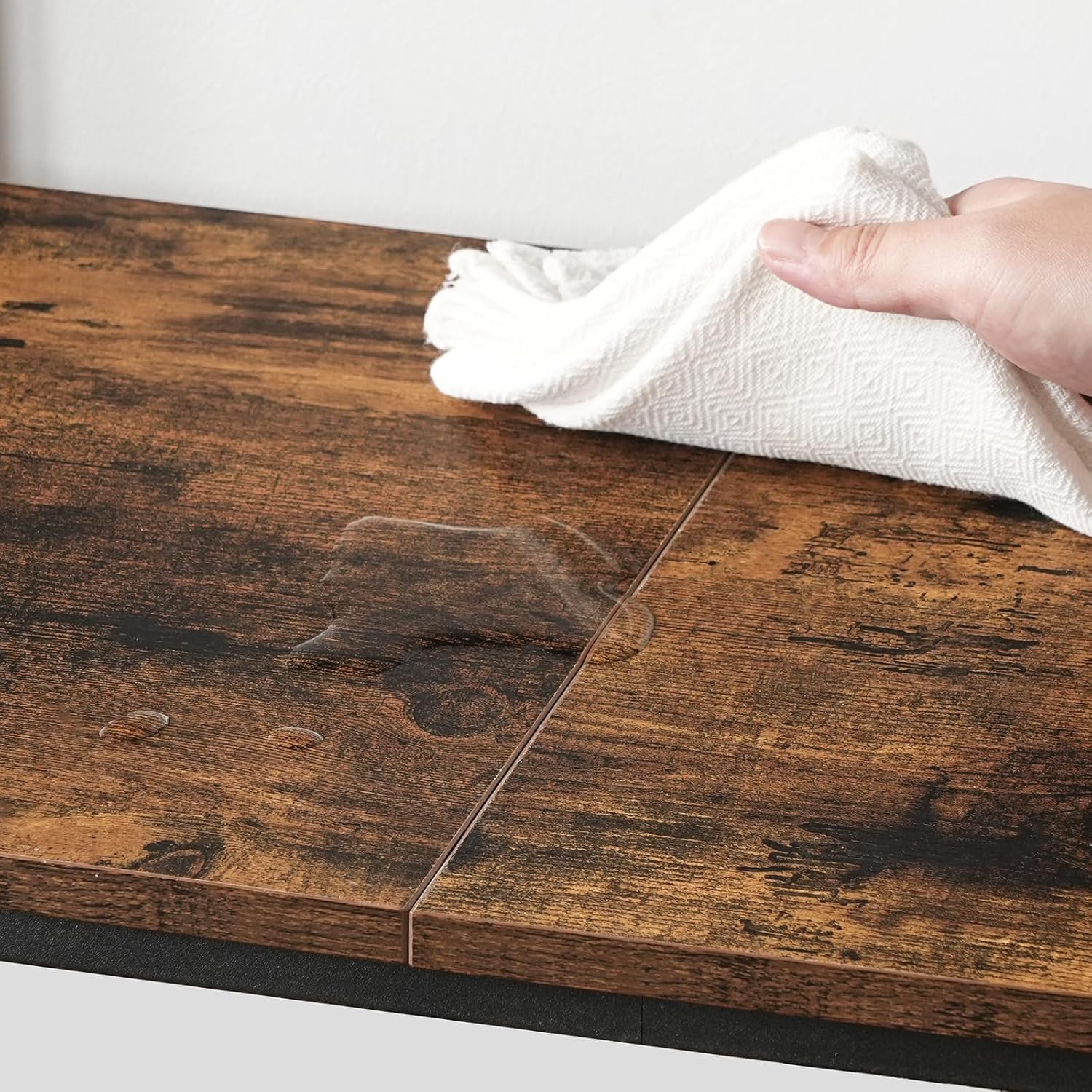 A hand wiping a spill from the wooden surface of the baker's rack