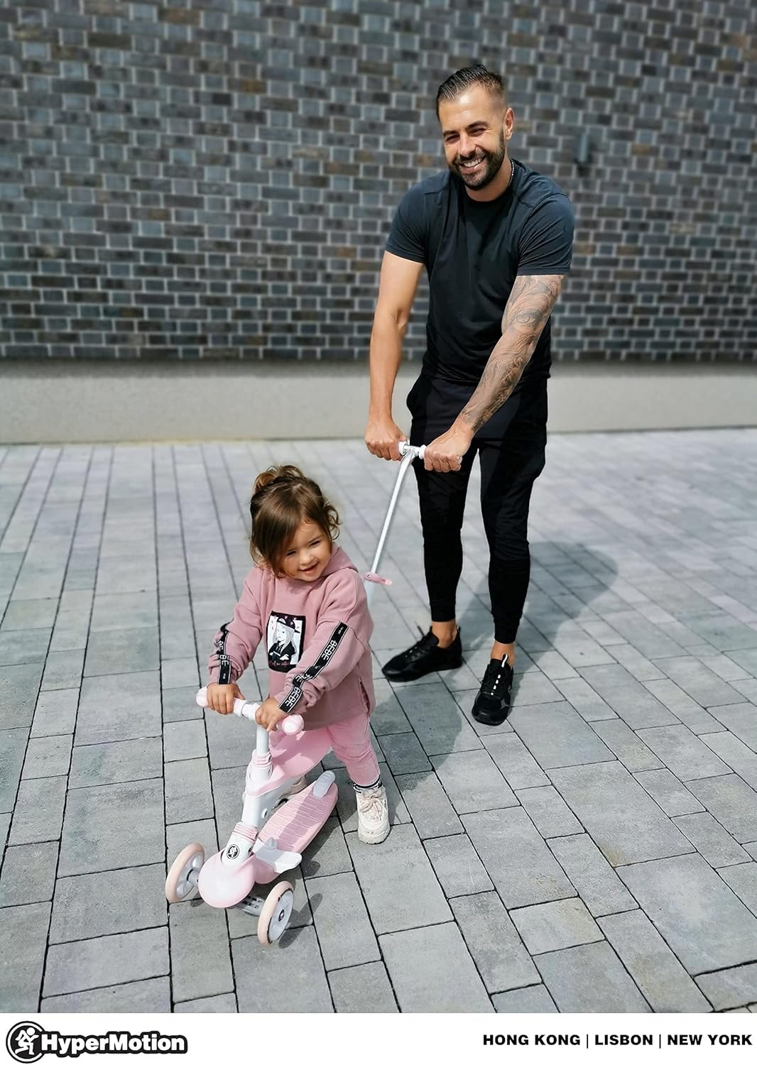 Adult pushing a child on the HyperMotion scooter tricycle in tricycle mode