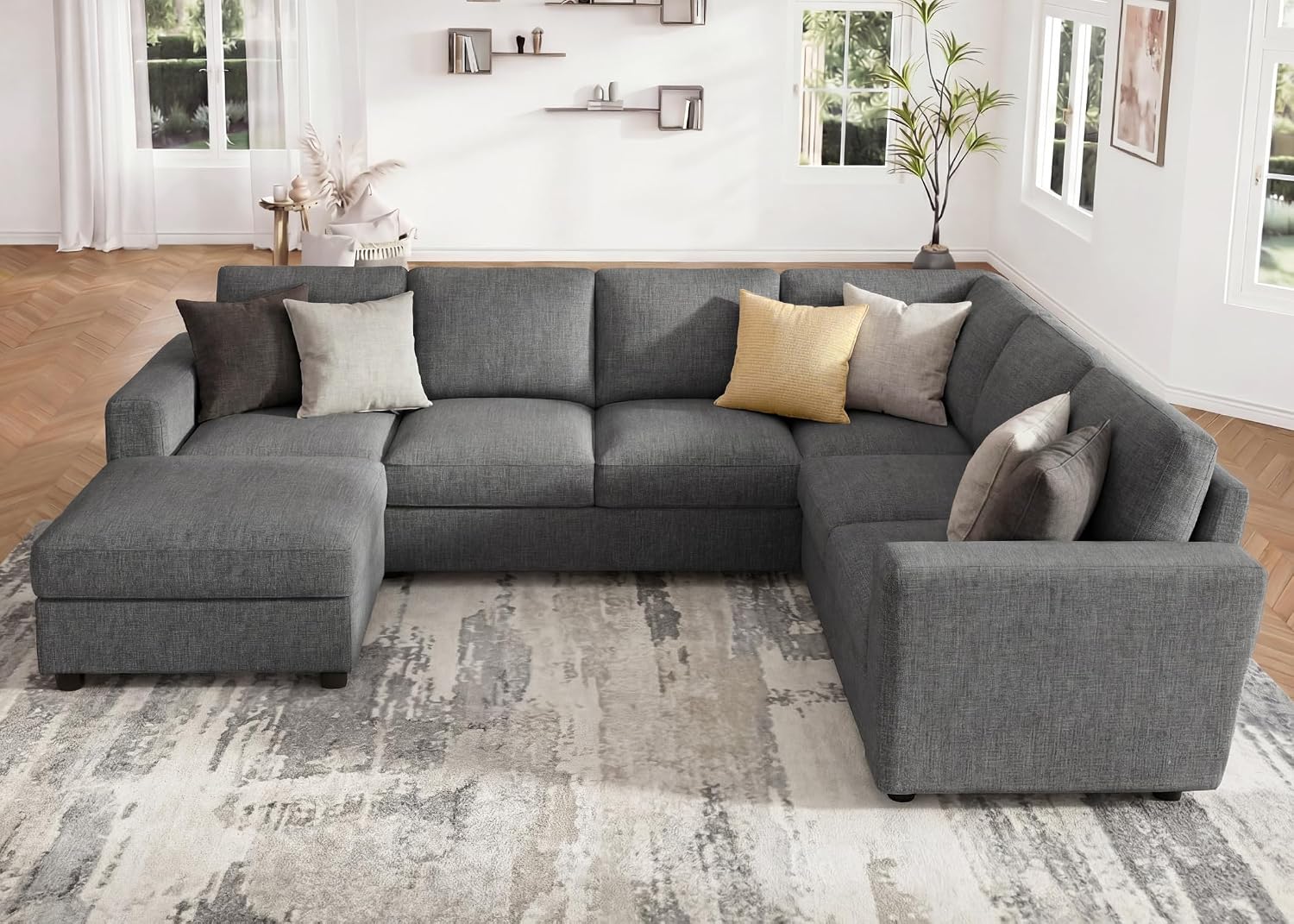 A light grey U-shape sectional sofa with a chaise lounge and several decorative pillows in a modern living room setting.