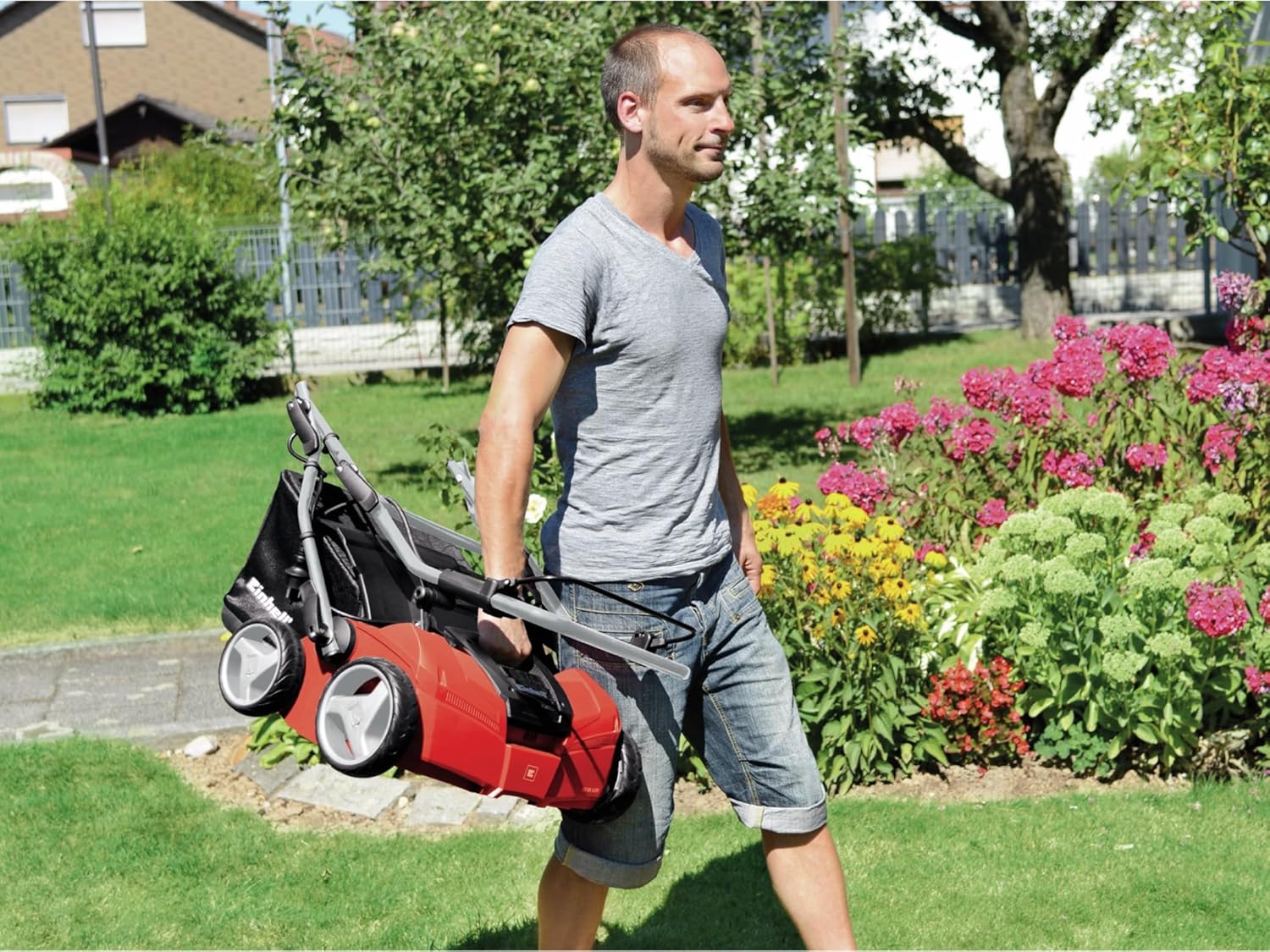 Image of a man carrying the folded Einhell GE-SA 1435 scarifier, demonstrating its portability and compact storage