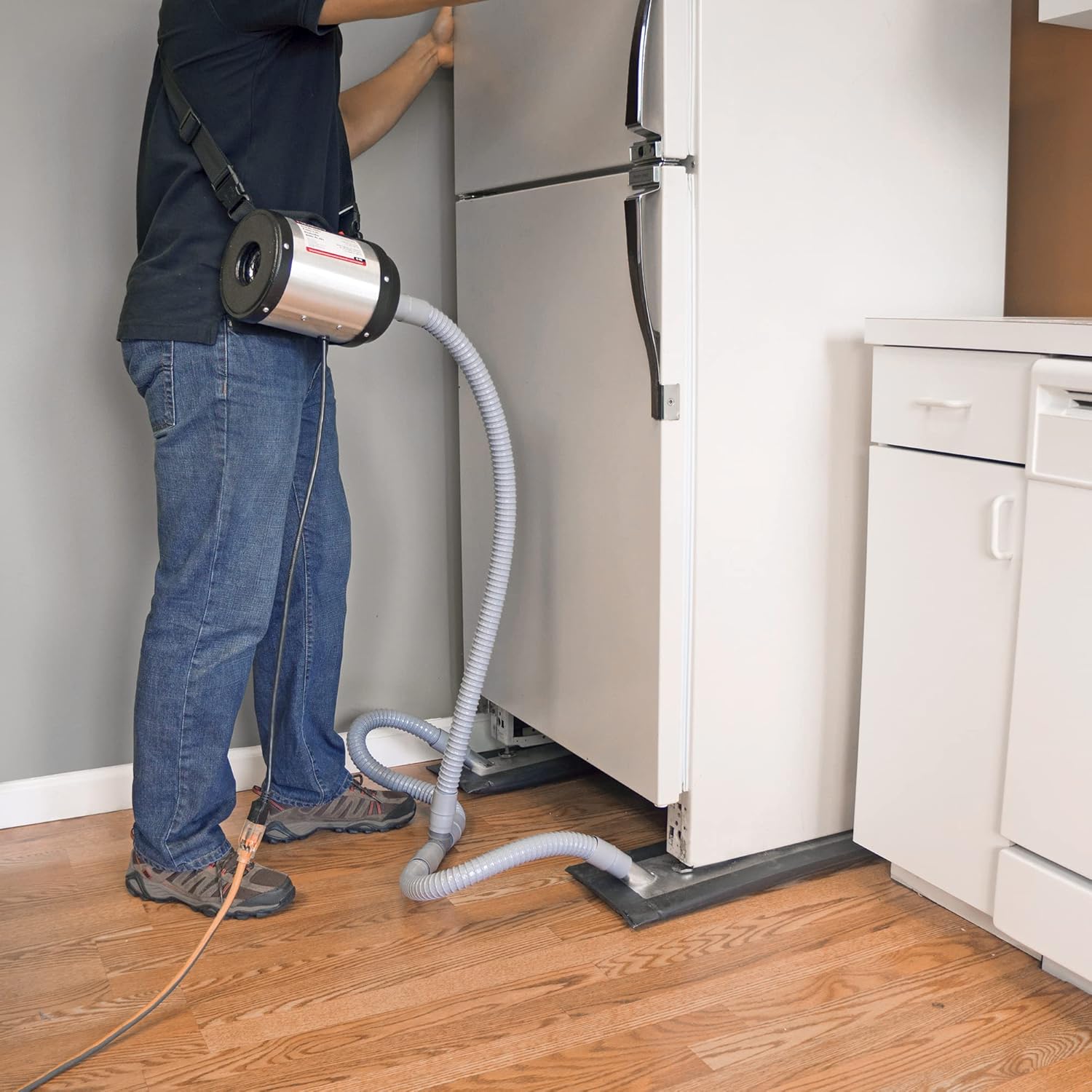 A person operating the ROBERTS 10-480 Dual Air Glider to move a large refrigerator across a hardwood floor, demonstrating the air-lifting principle.