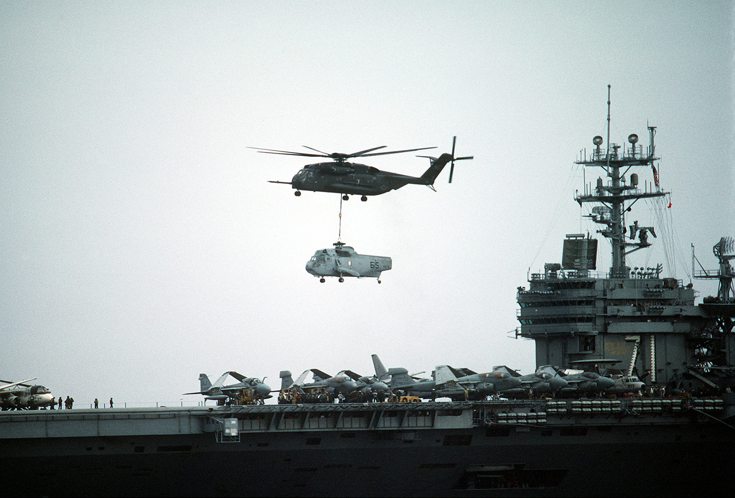 A Helicopter Combat Support Squadron 4 (HC-4) CH-53E Super Stallion helicopter lifts a partially dismantled Helicopter Anti-submarine Squadron 9 (HS-9) - 12 Inch by 18 Inch Laminated Poster - Bright Colors And Vivid Imagery