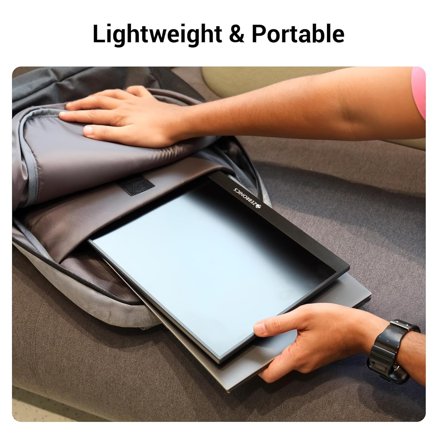 A person carefully placing the lightweight ZEBRONICS Pixigo A16 portable monitor into a backpack, demonstrating its portability.