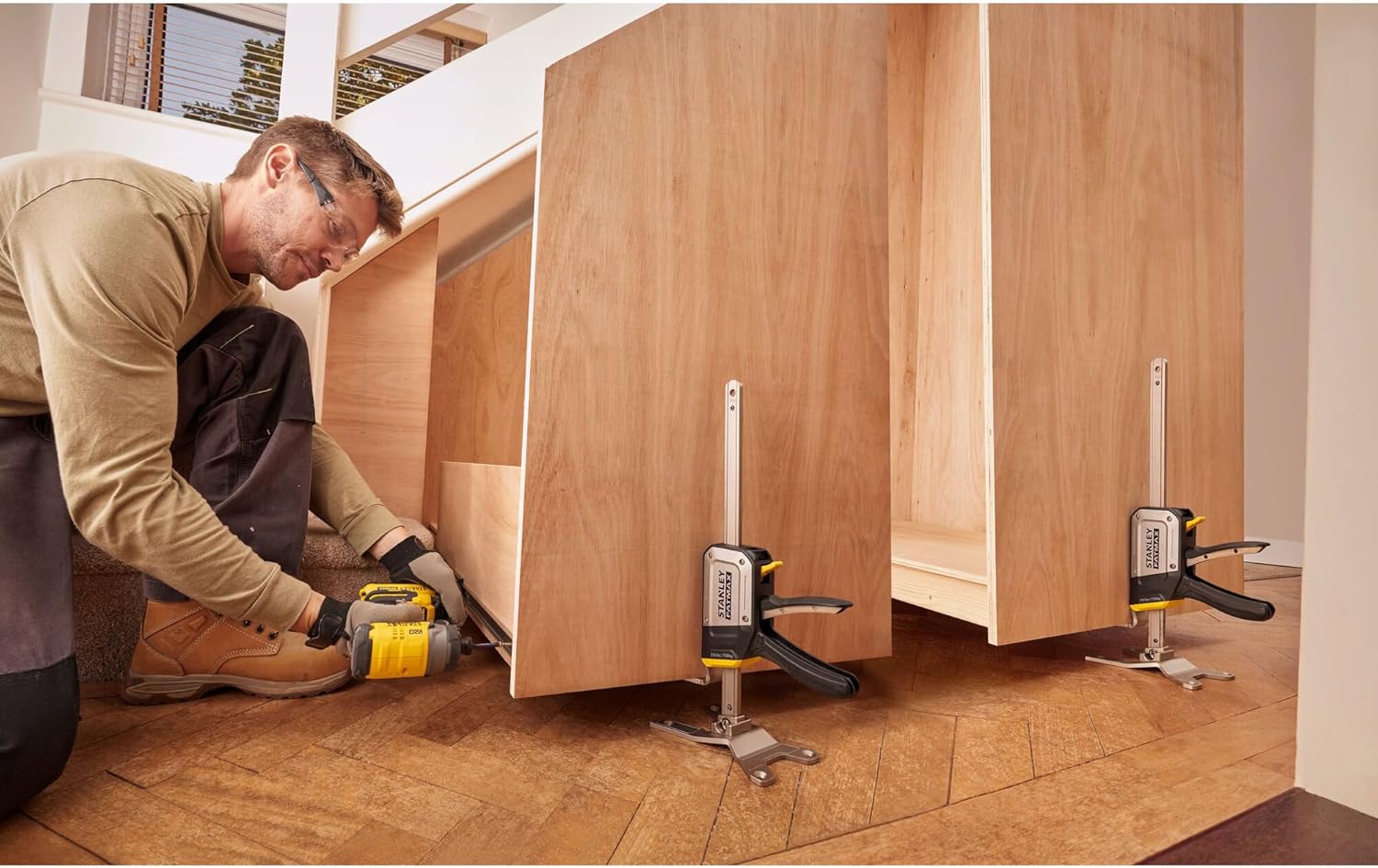 A person using two STANLEY FATMAX TradeLift tools to support a large wooden panel.