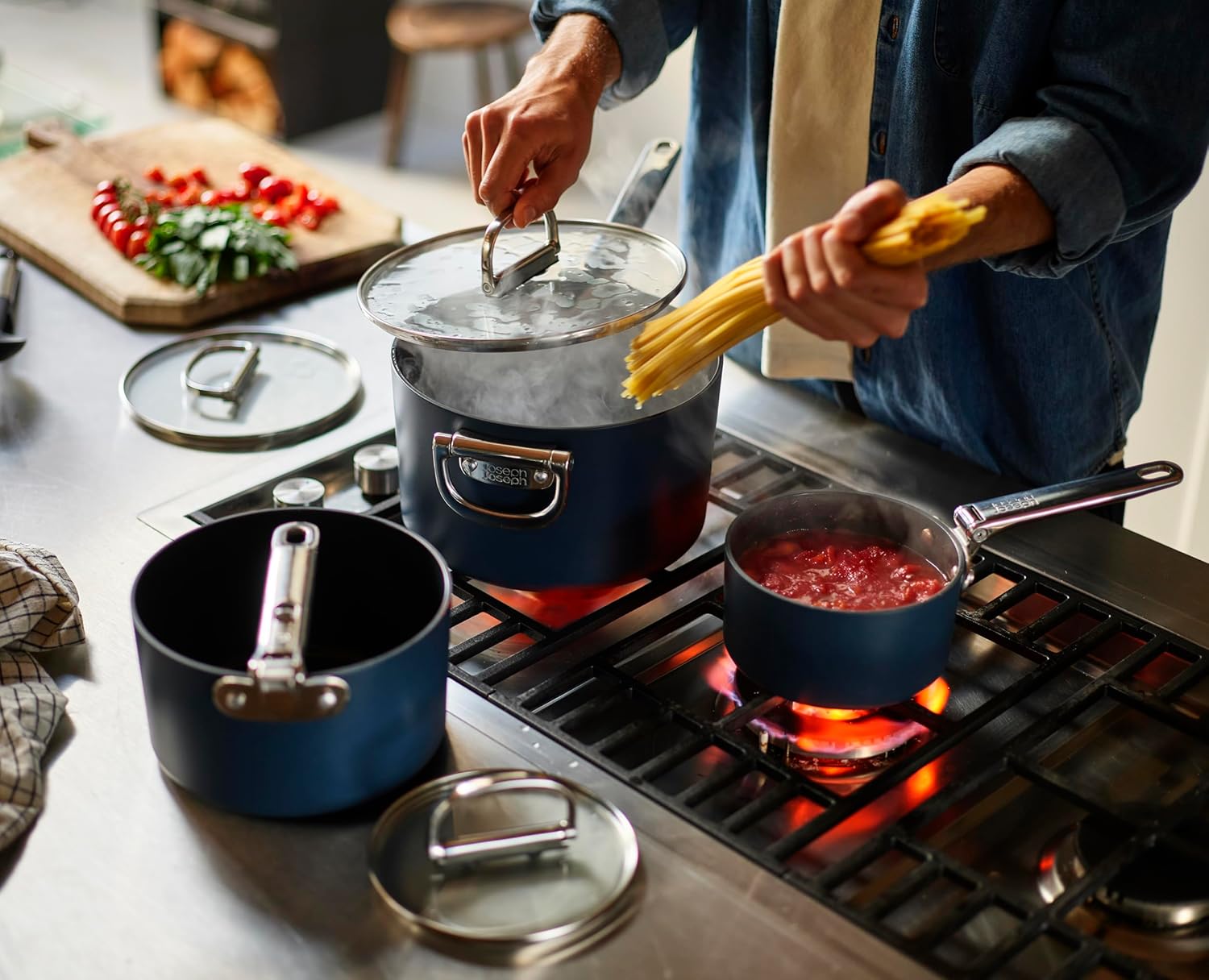 Person cooking pasta and sauce using Joseph Joseph Space saucepans on a stovetop