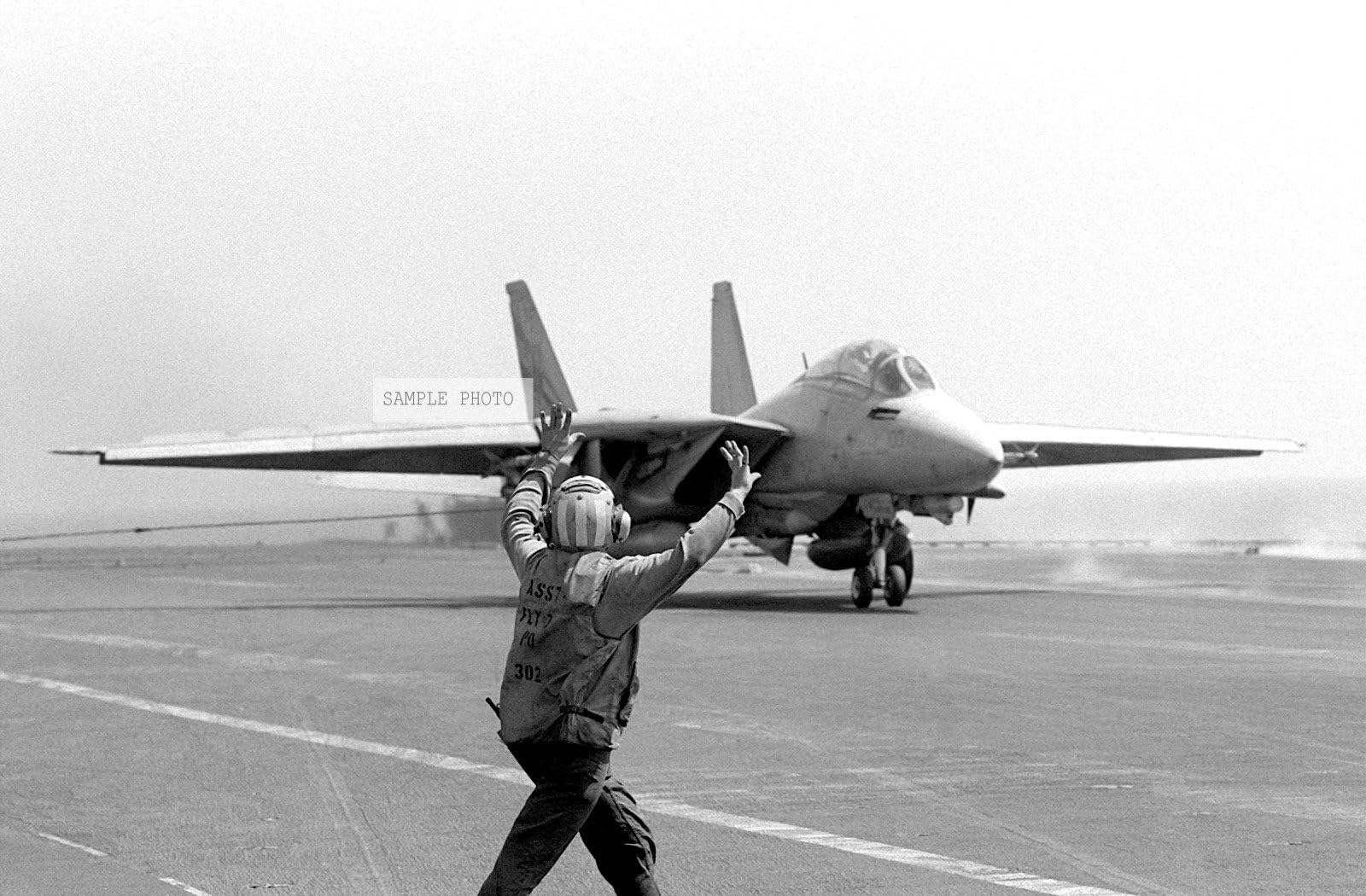 Photo An F-14 Tomcat aircraft stops after landing on the flight deck of the aircraft carrier USS INDEPENDENCE (CV-62). The INDEPENDENCE is participating in Operation Southern Watch, a multinational effort establishing a no-fly zone for Iraqi aircraft south of the 32nd parallel in Iraq. The crewman in the foreground gives the pilot the stop sign, 08/29/1992