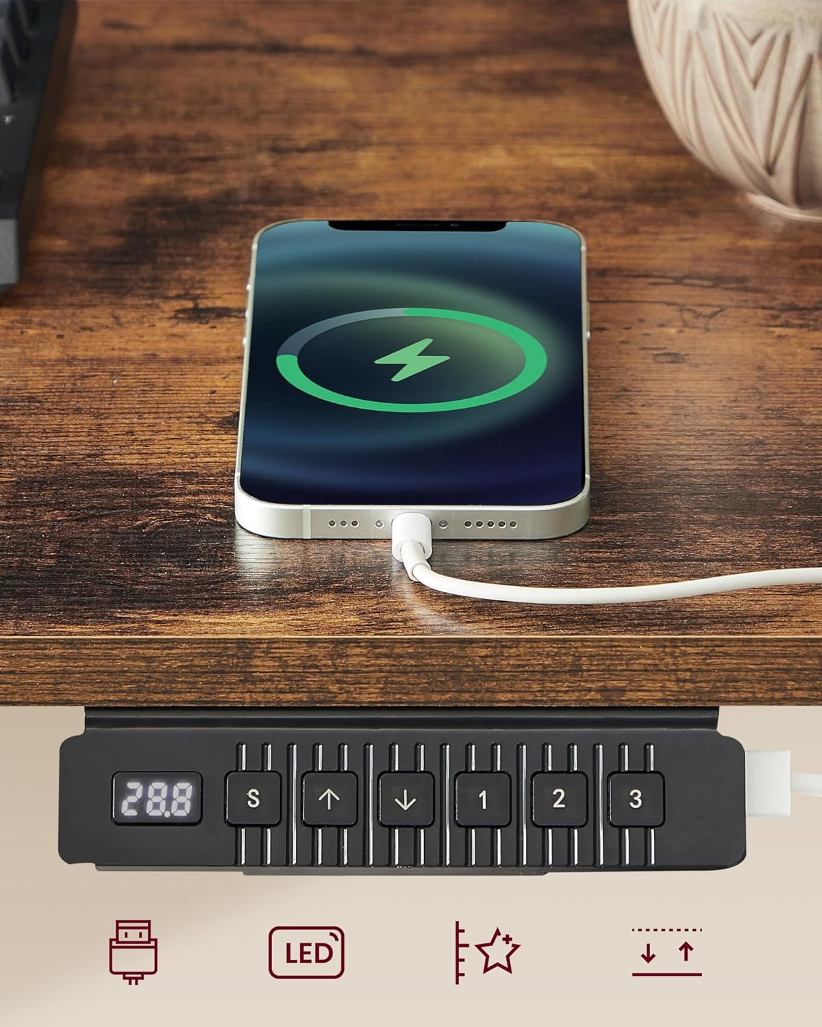 Close-up of the desk control panel and a phone charging on the desk