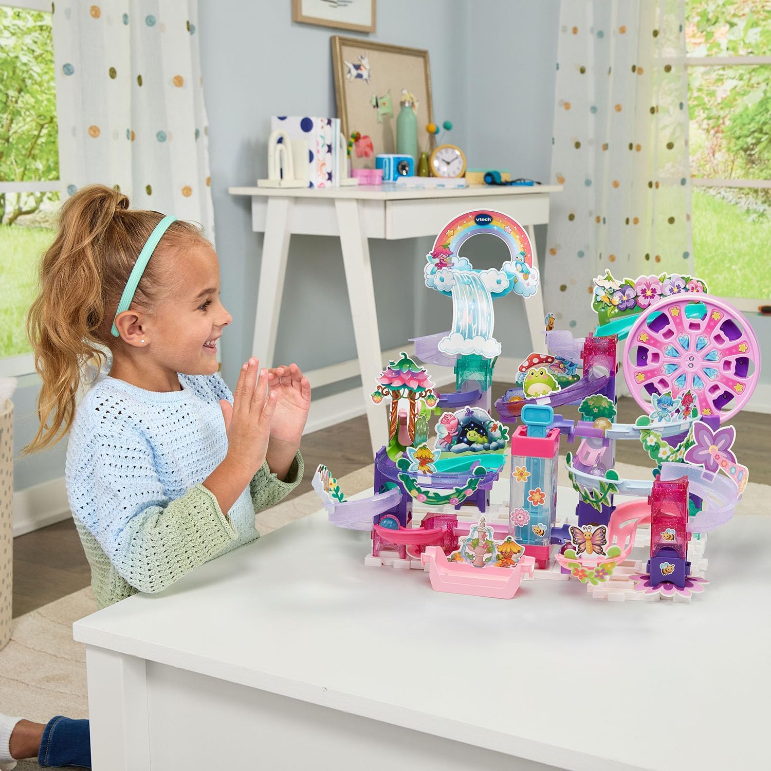 A young girl happily playing with the fully assembled VTech Marble Rush Magic Fairyland Playset, watching marbles move through the course.