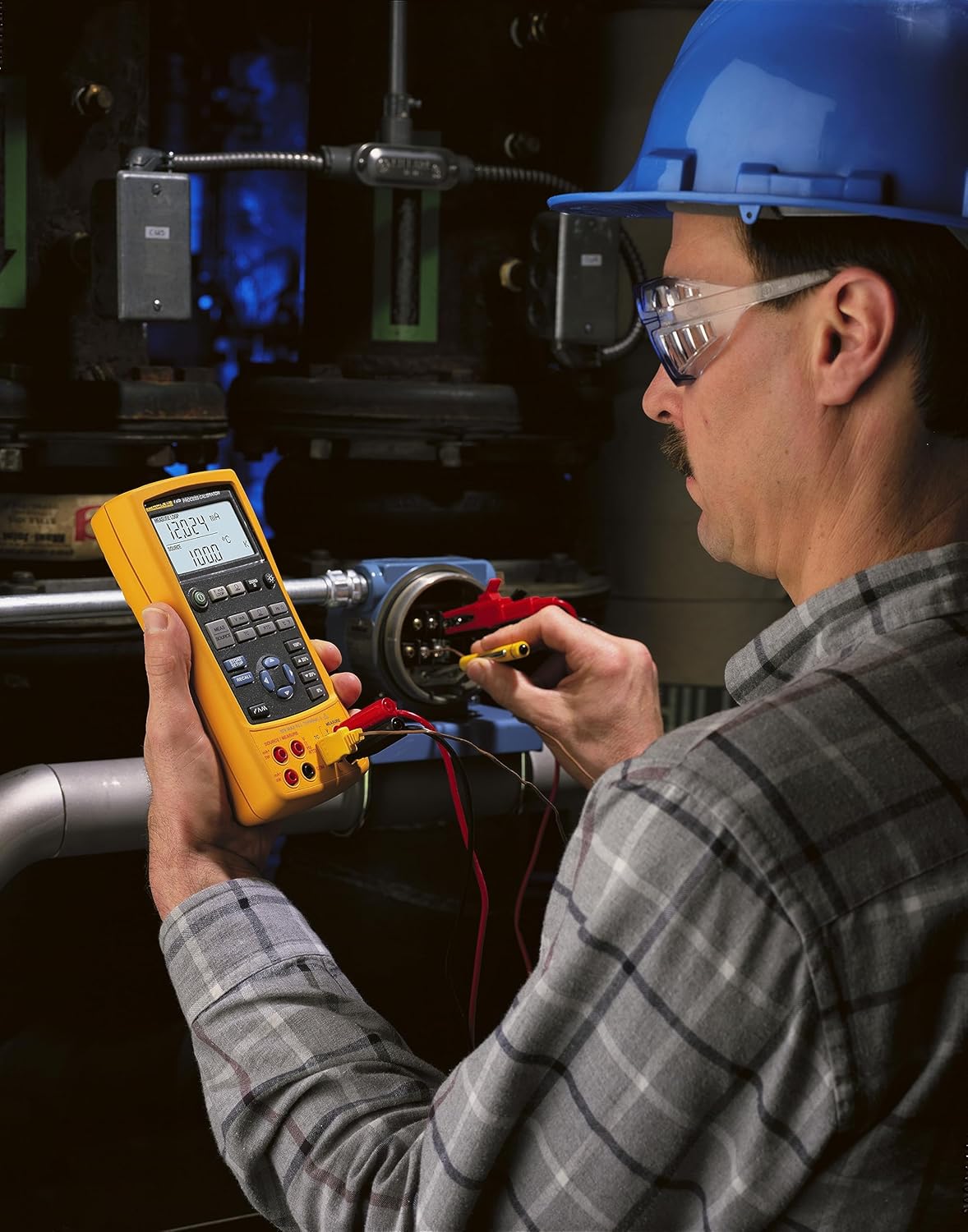 Technician using Fluke 725 calibrator to connect to industrial equipment