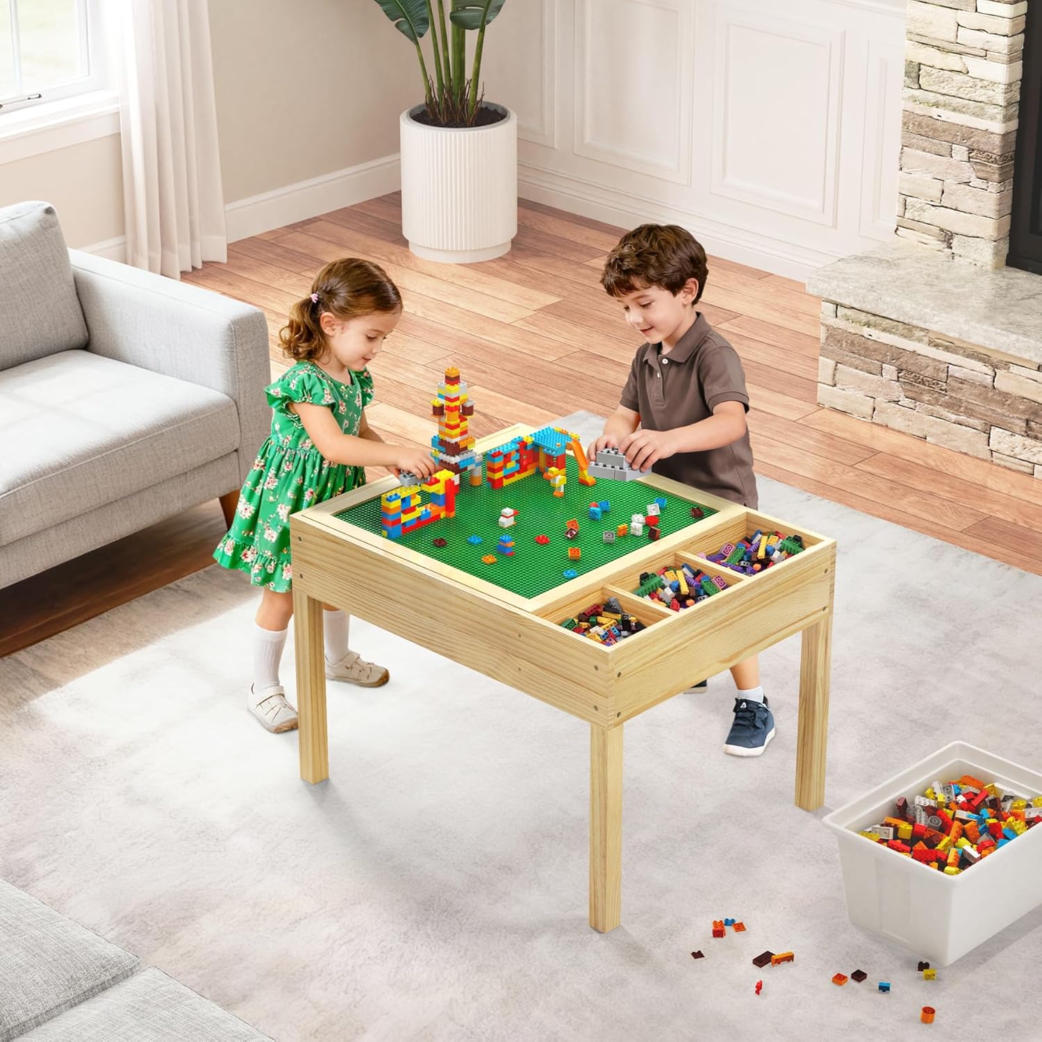 Two children playing with building bricks on the green baseplate of the activity table.