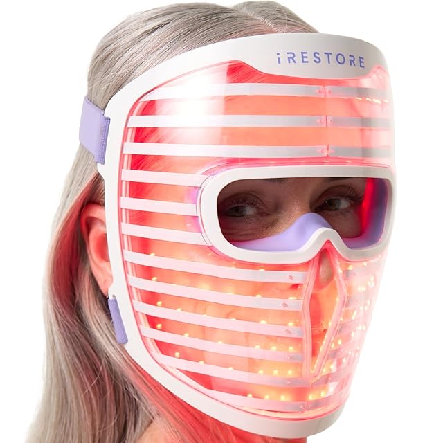 iRestore Illumina LED Face Mask — rigid hovering mask form factor with 360 visible LEDs glowing red, blue, and infrared, sized to cover the full face without skin contact, the FDA 510(k) Class II cleared mask from a 20-year laser-therapy R&D brand delivering 1,200 mW peak output across red 635nm, blue 415nm, and infrared 830nm wavelengths during 10-minute sessions 3-5 times per week