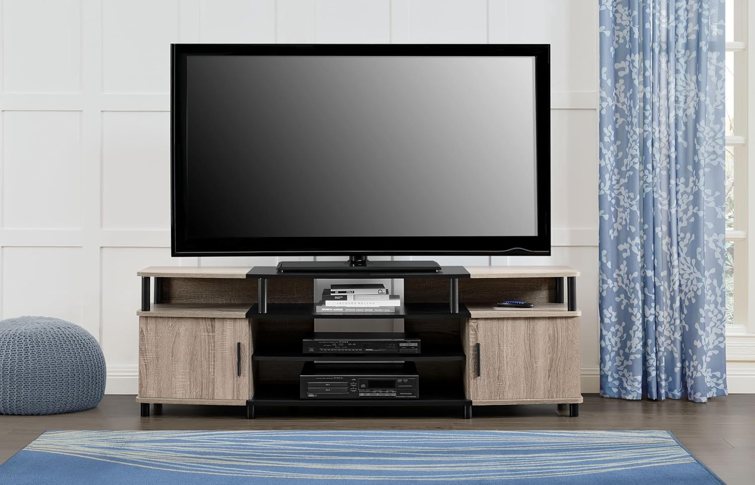 Ameriwood Home Carson TV Stand in a living room setting, supporting a large television and housing media devices.