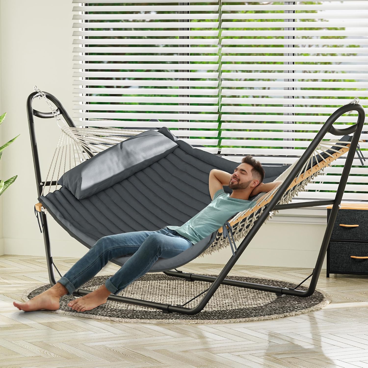 A person relaxing comfortably in the YITAHOME Hammock with Stand indoors.