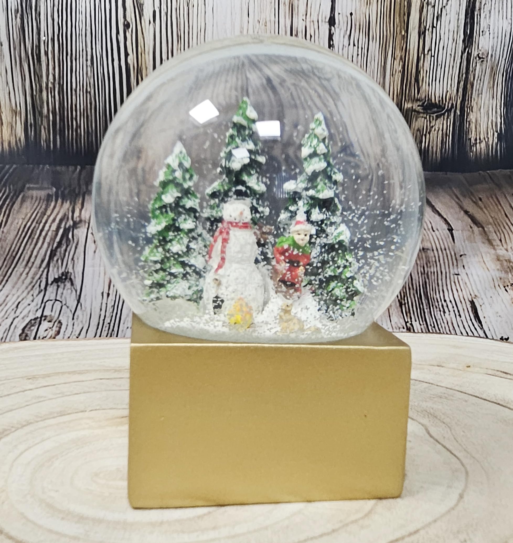 Weihnachts-Schneekugel Winterstimmung | Schneemann Steht mit Kind auf Schlitten | Sockel Farbe Gold | 100mm breit, 120mm hoch | Bezaubernde Schüttelkugel | Weihnachtsdekoration | 20238