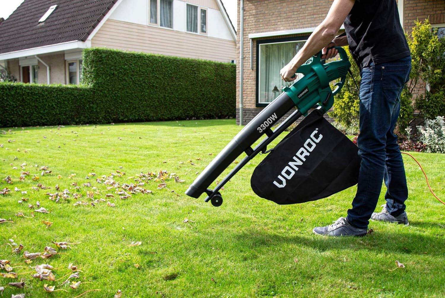 Person using the VONROC Leaf Blower to clear leaves from a grassy lawn.