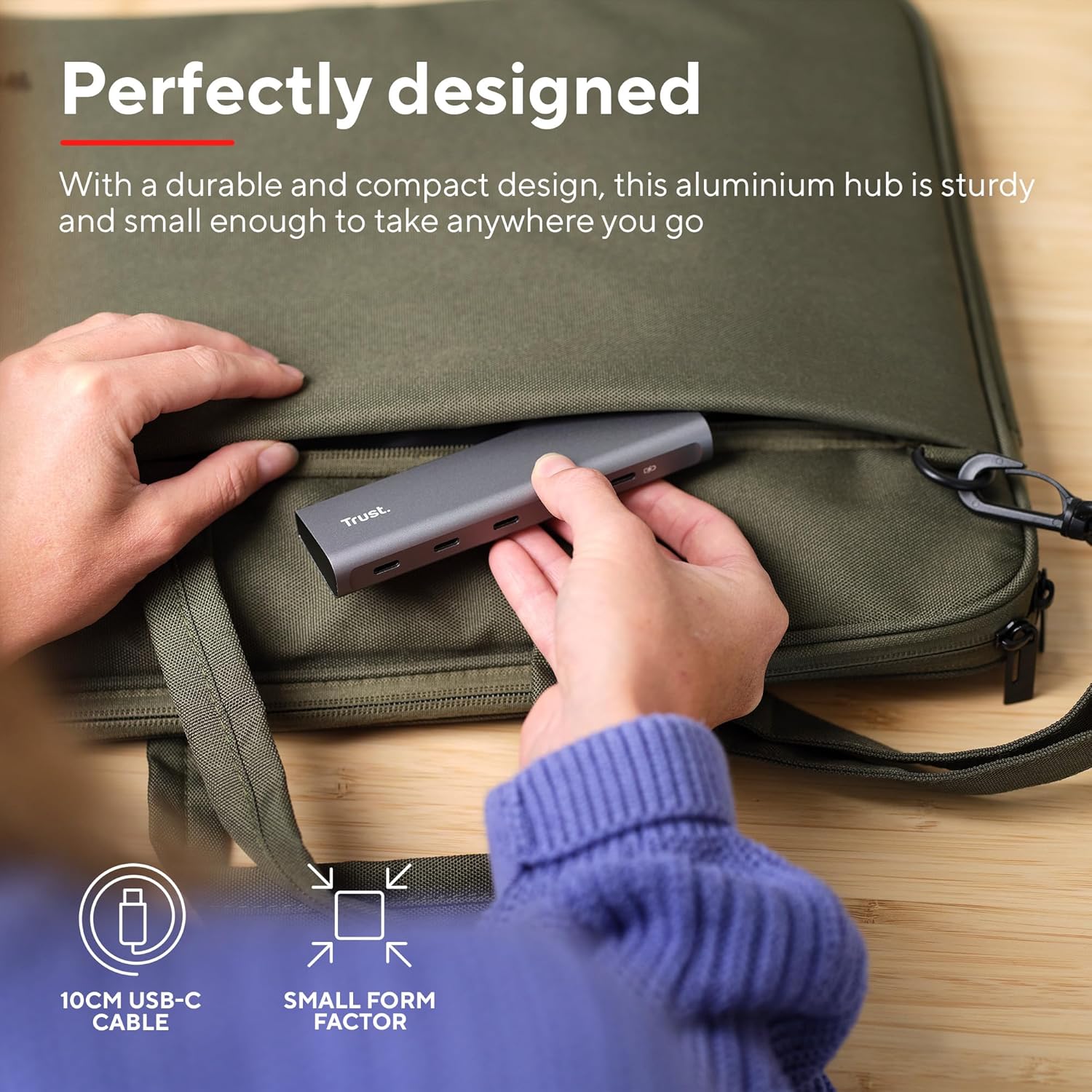 Hand placing the Trust Halyx USB-C Hub into a laptop bag