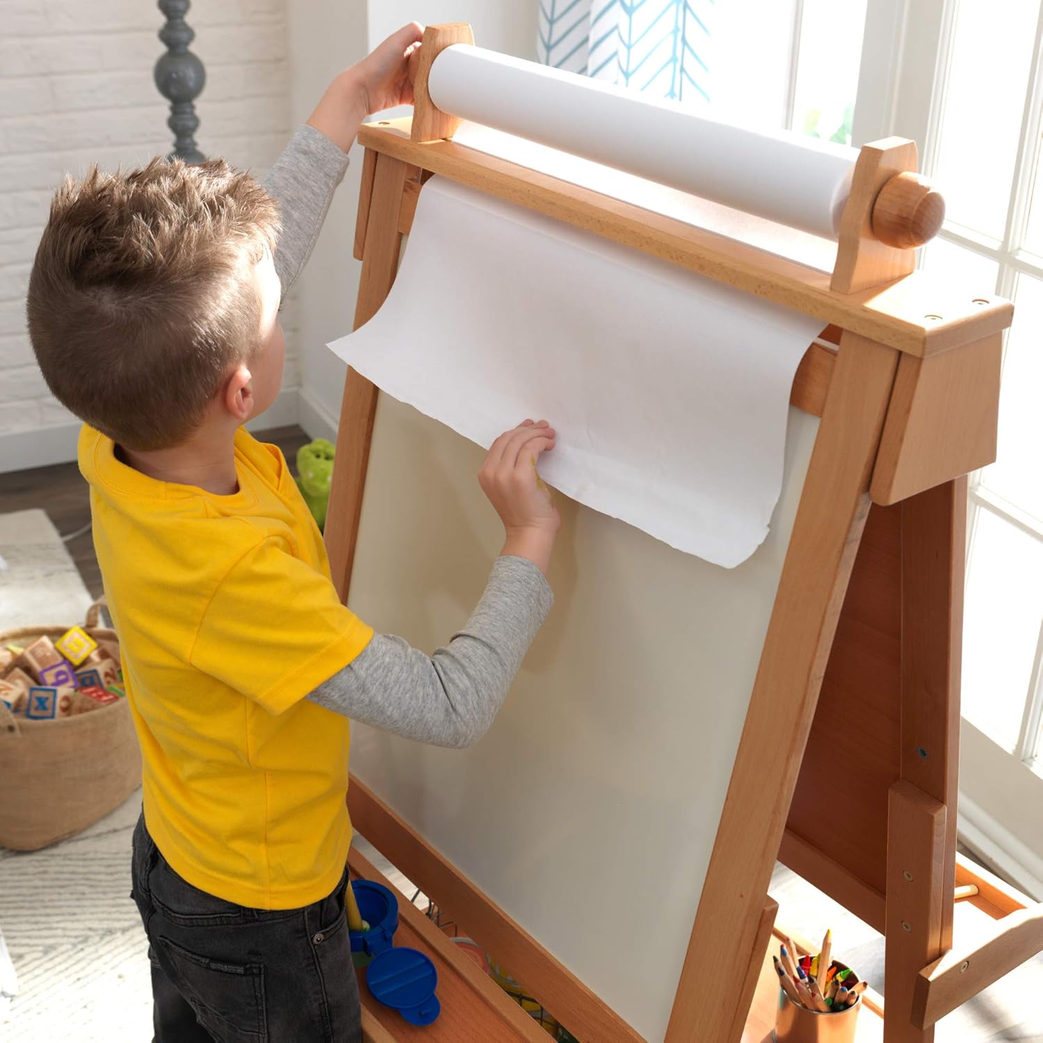 A child adjusting the paper roll on the top holder of the easel.