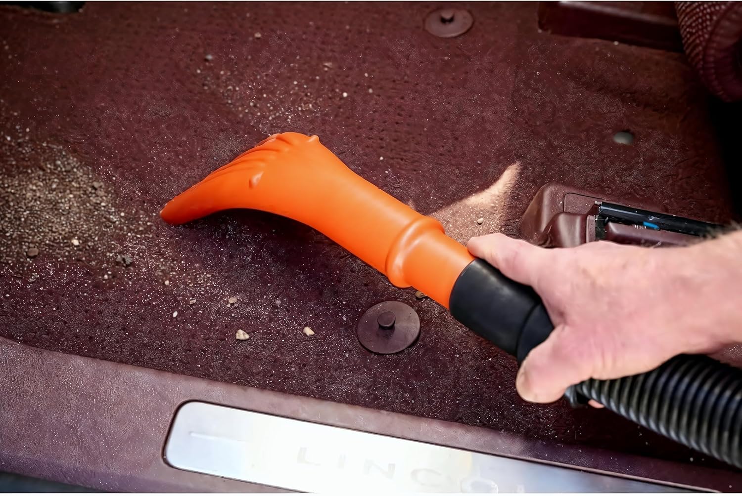 A person using the MetroVac Super Vac N Blaster to blow water off a car's headlight and fender after washing.