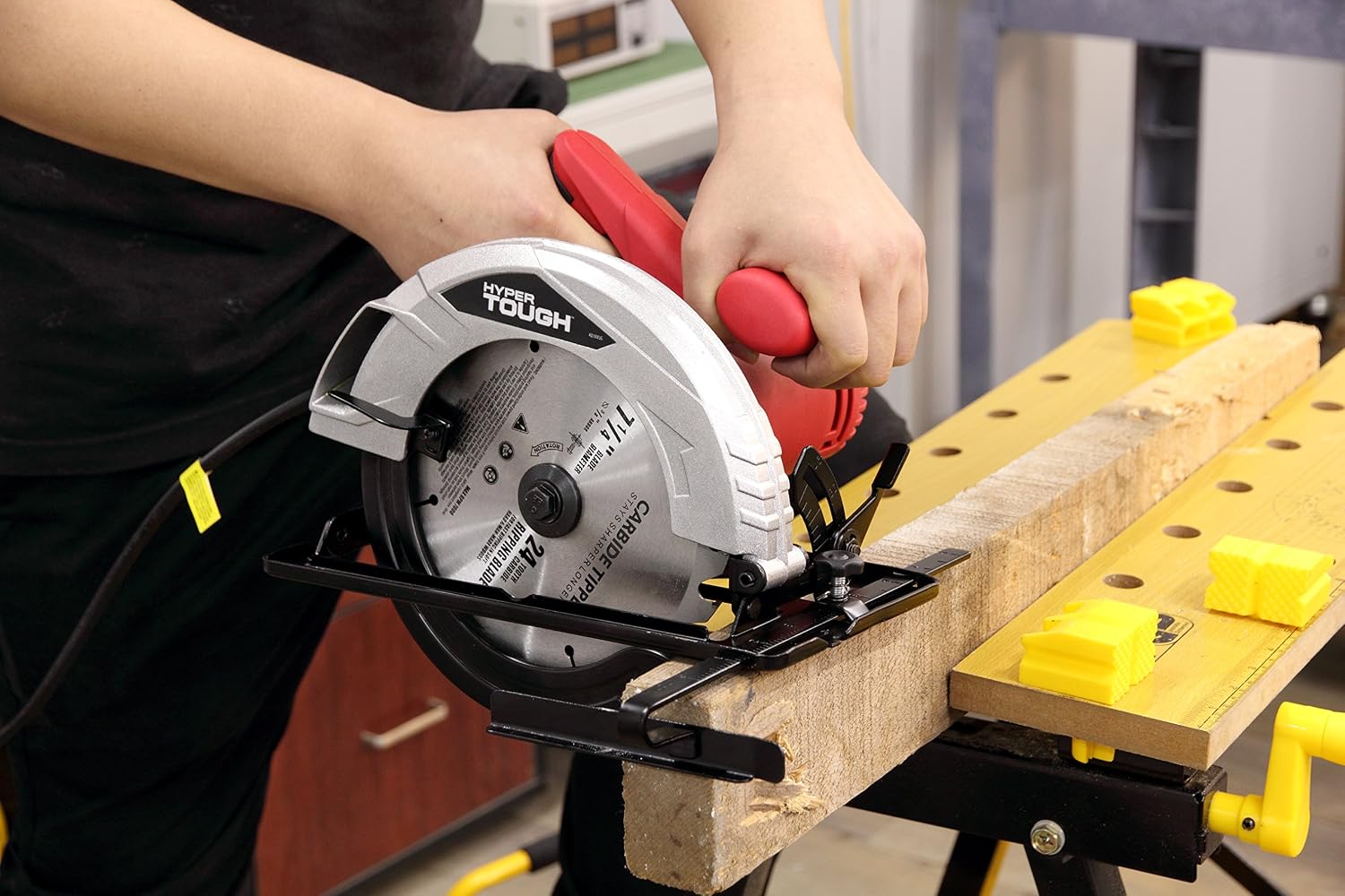 Person operating Hyper Tough circular saw to cut a wooden board