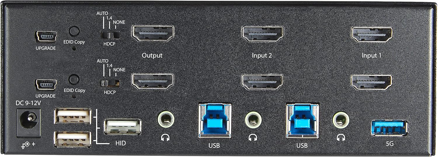 Tukangeun view of the StarTech.com KVM switch showing power input, upgrade port, EDID/HDCP switches, HDMI output ports, HDMI input ports for two computers, USB 3.0 ports, and audio jacks.