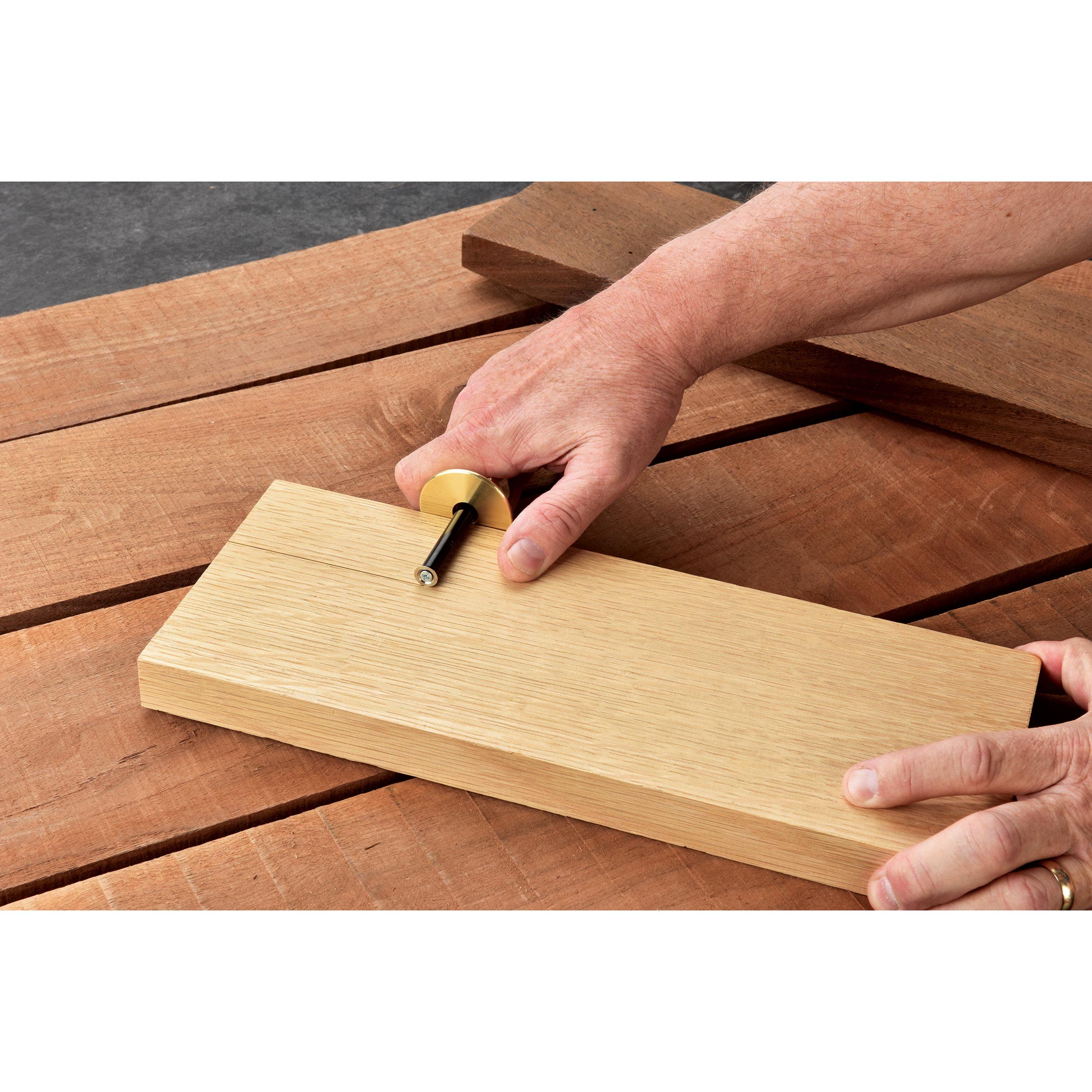 User holding the marking gauge against a wooden board