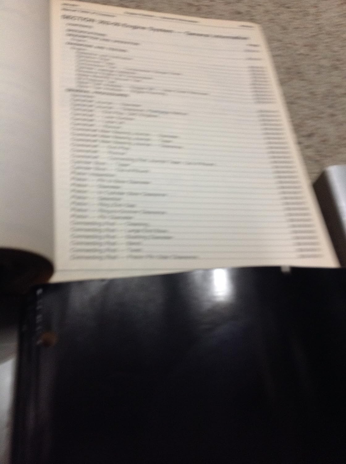 Open page of a repair manual showing a list of engine system components and specifications.