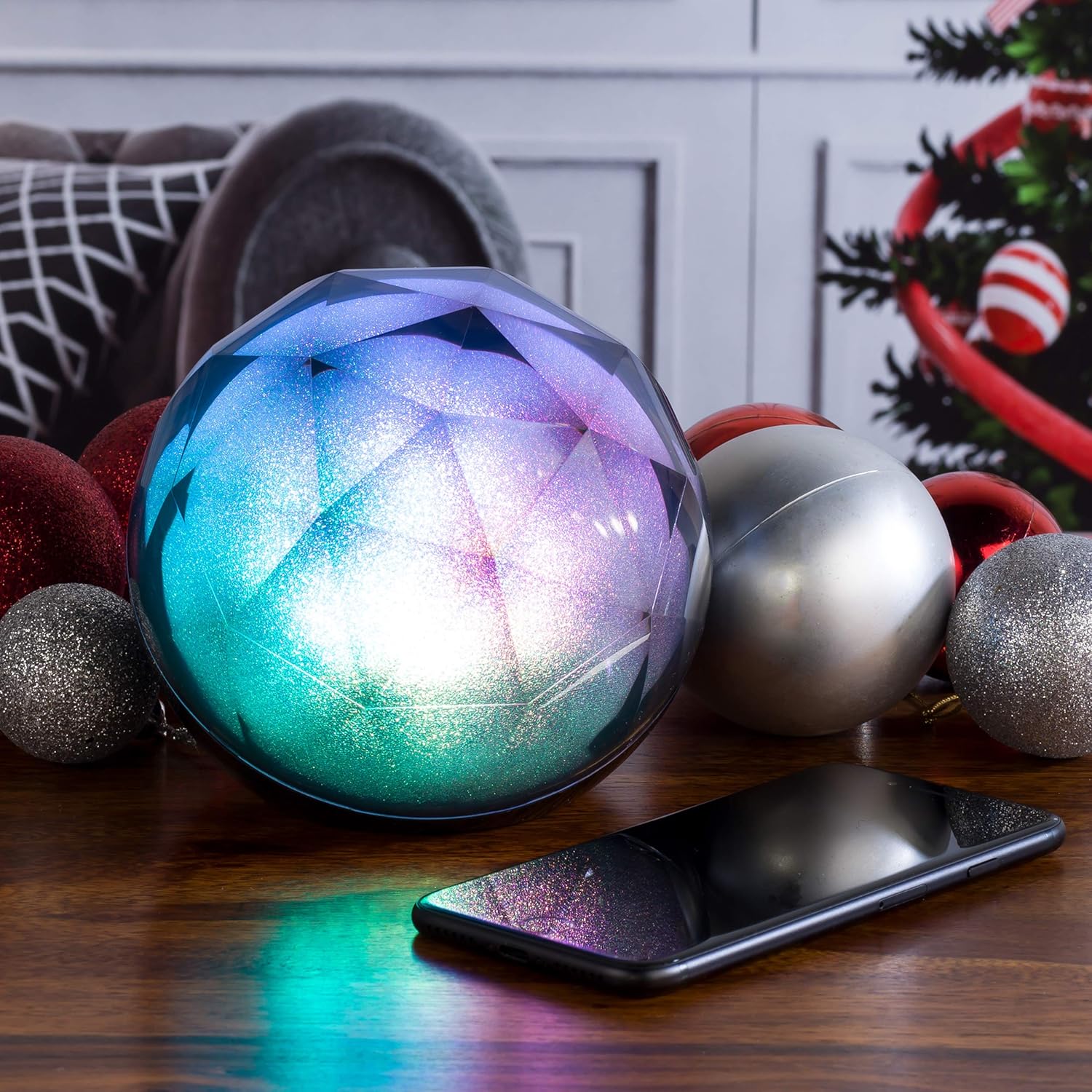 Intempo Geode Glitter Ball Bluetooth Speaker next to a smartphone, both illuminated