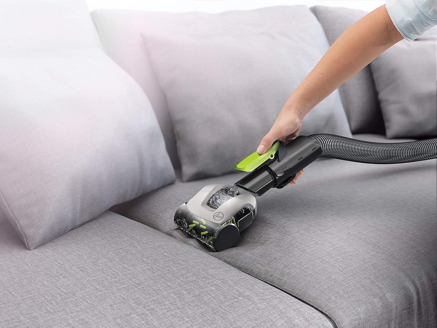 Hand using pet hair tool on a sofa cushion