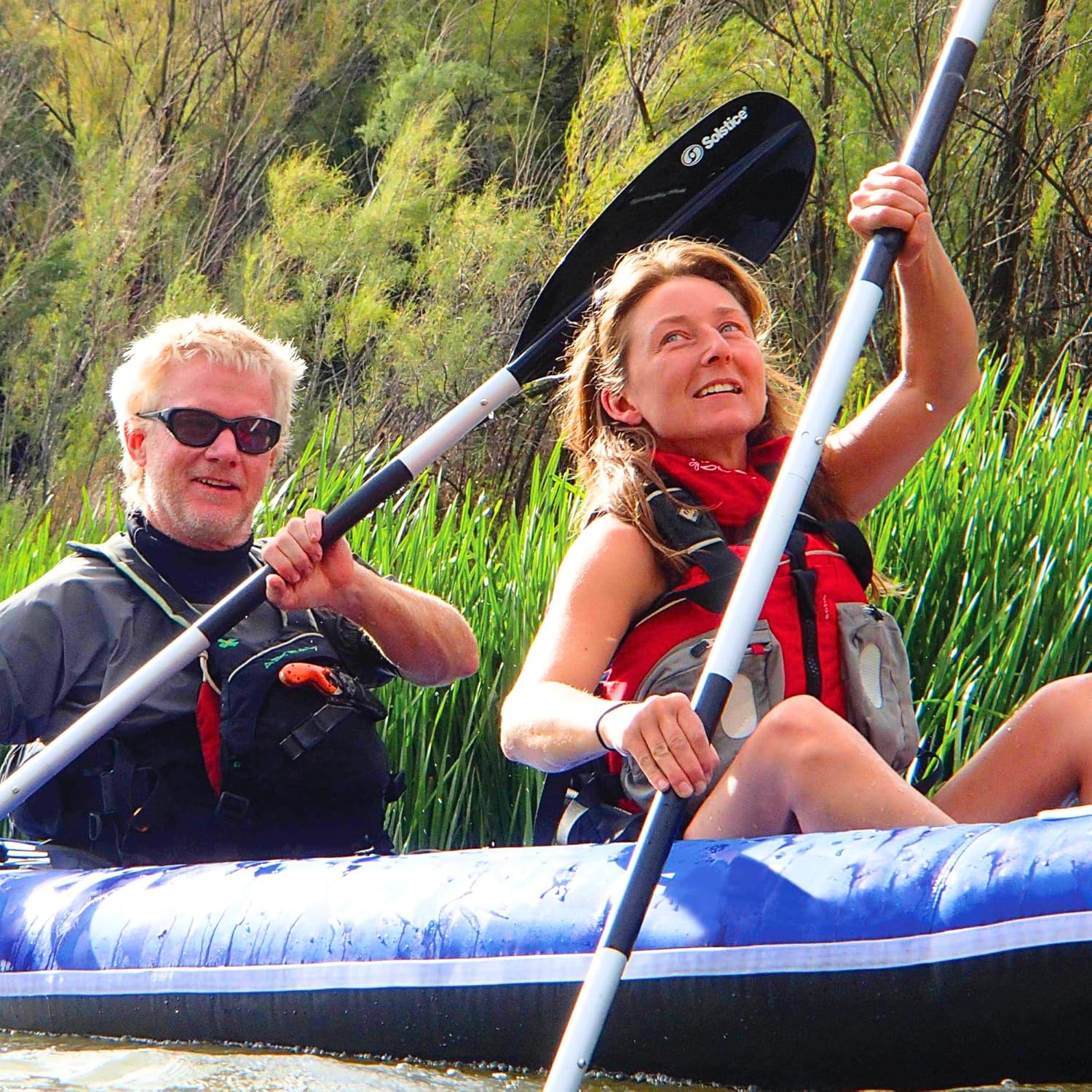 Two individuals paddling the SOLSTICE Durango Inflatable Kayak on a calm river.