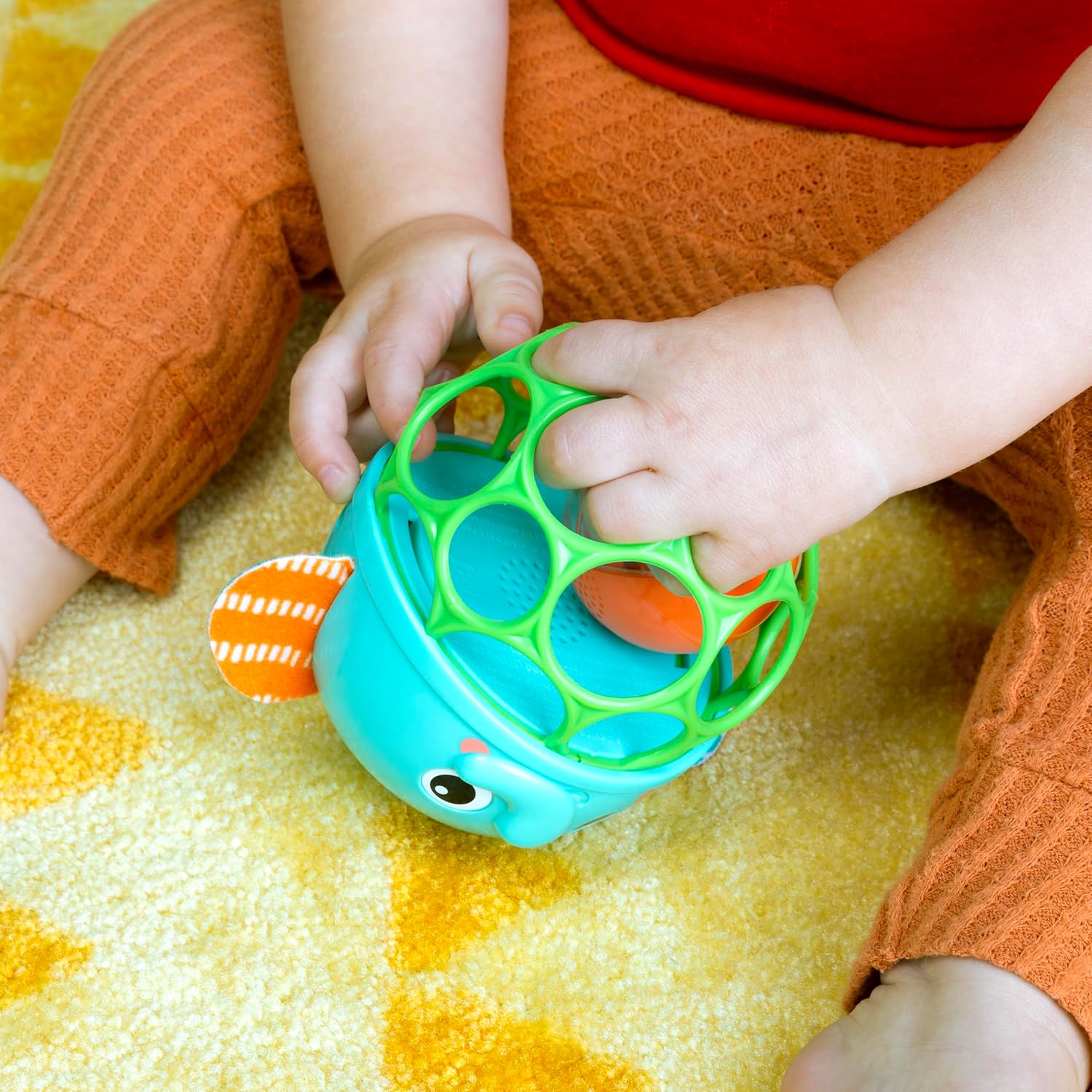 Baby's hands holding the Bright Starts Giggle & Glow Elephant Toy, demonstrating easy grasping.