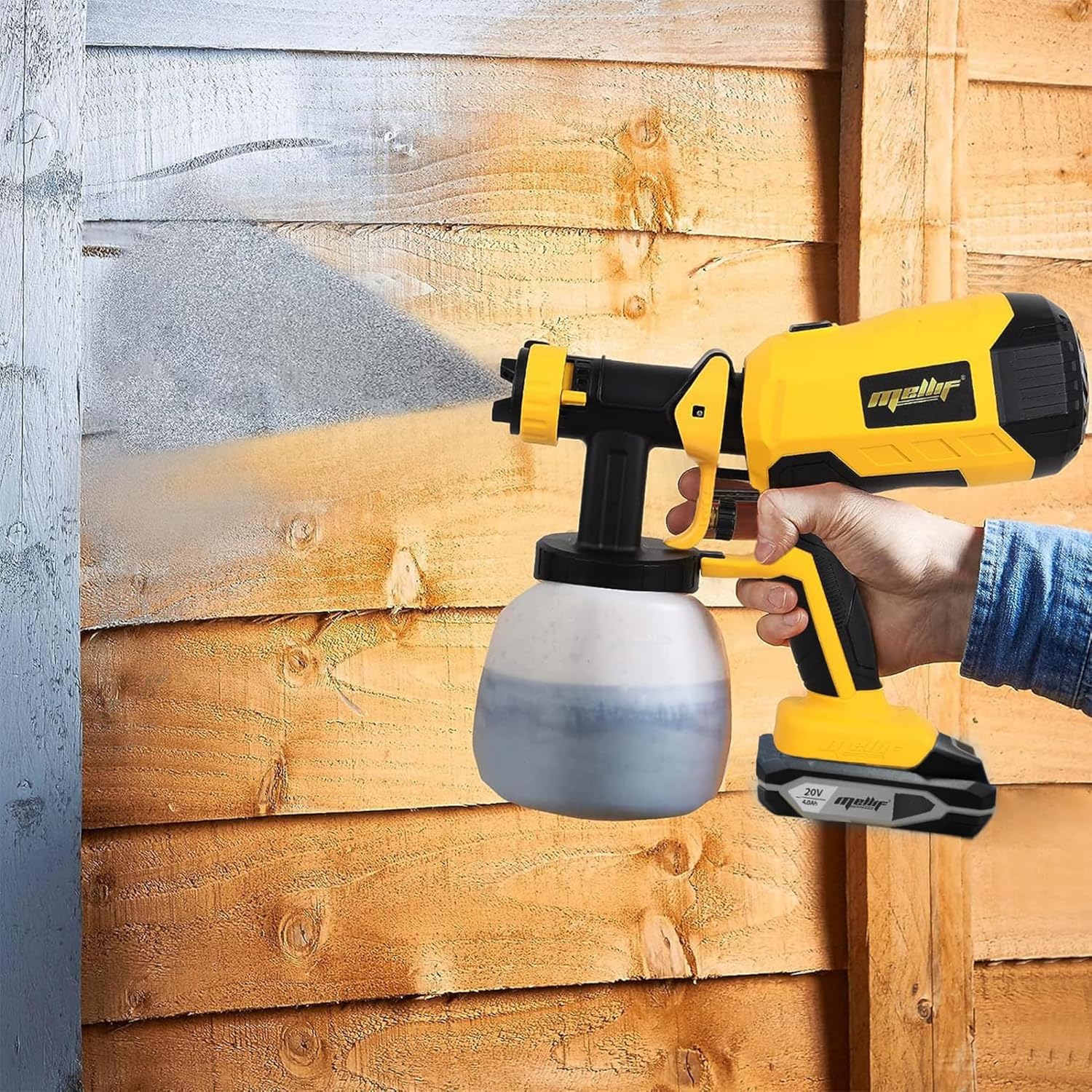 A person using the Mellif paint sprayer to paint a wooden fence, demonstrating coverage on outdoor surfaces.
