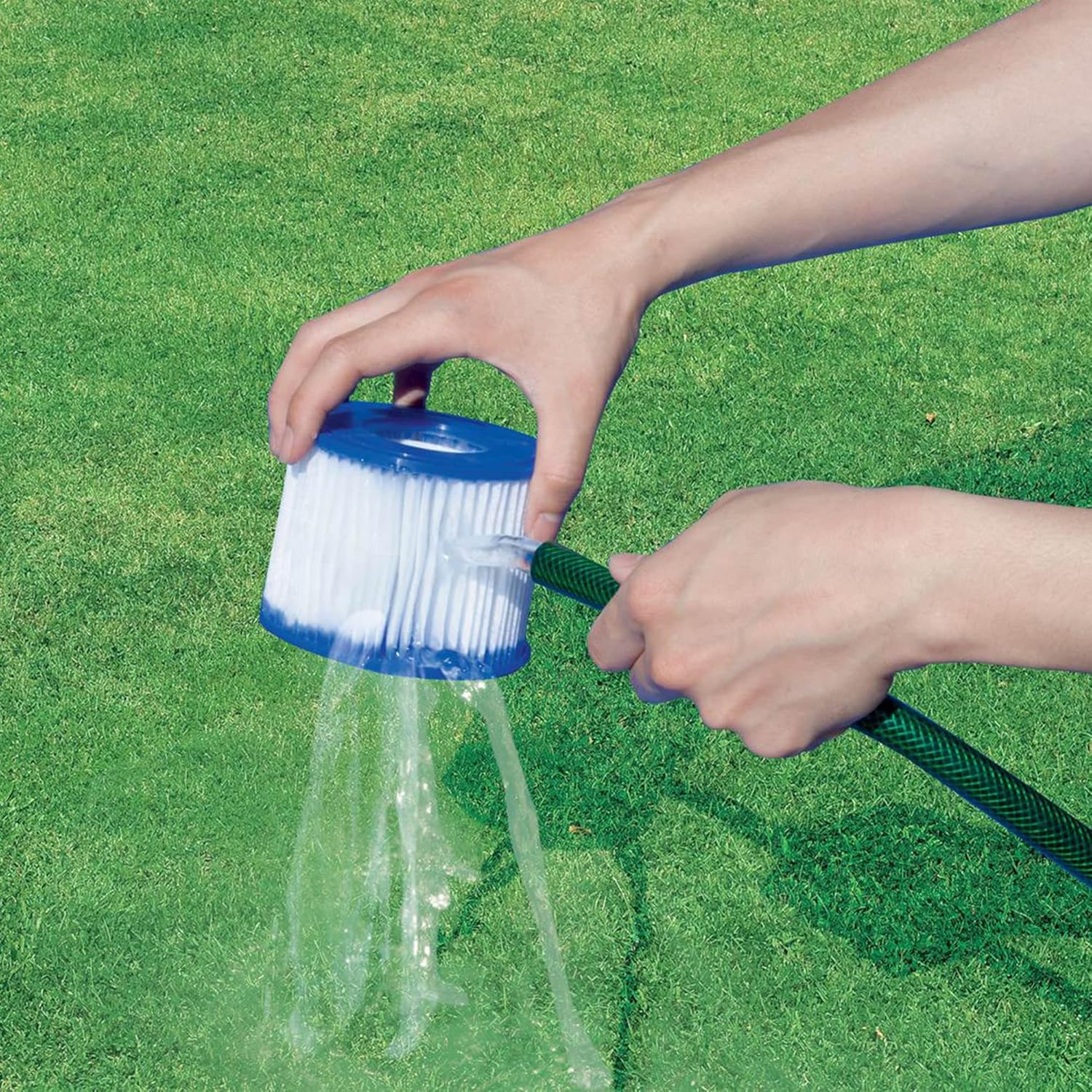 Hands cleaning a filter cartridge with a hose