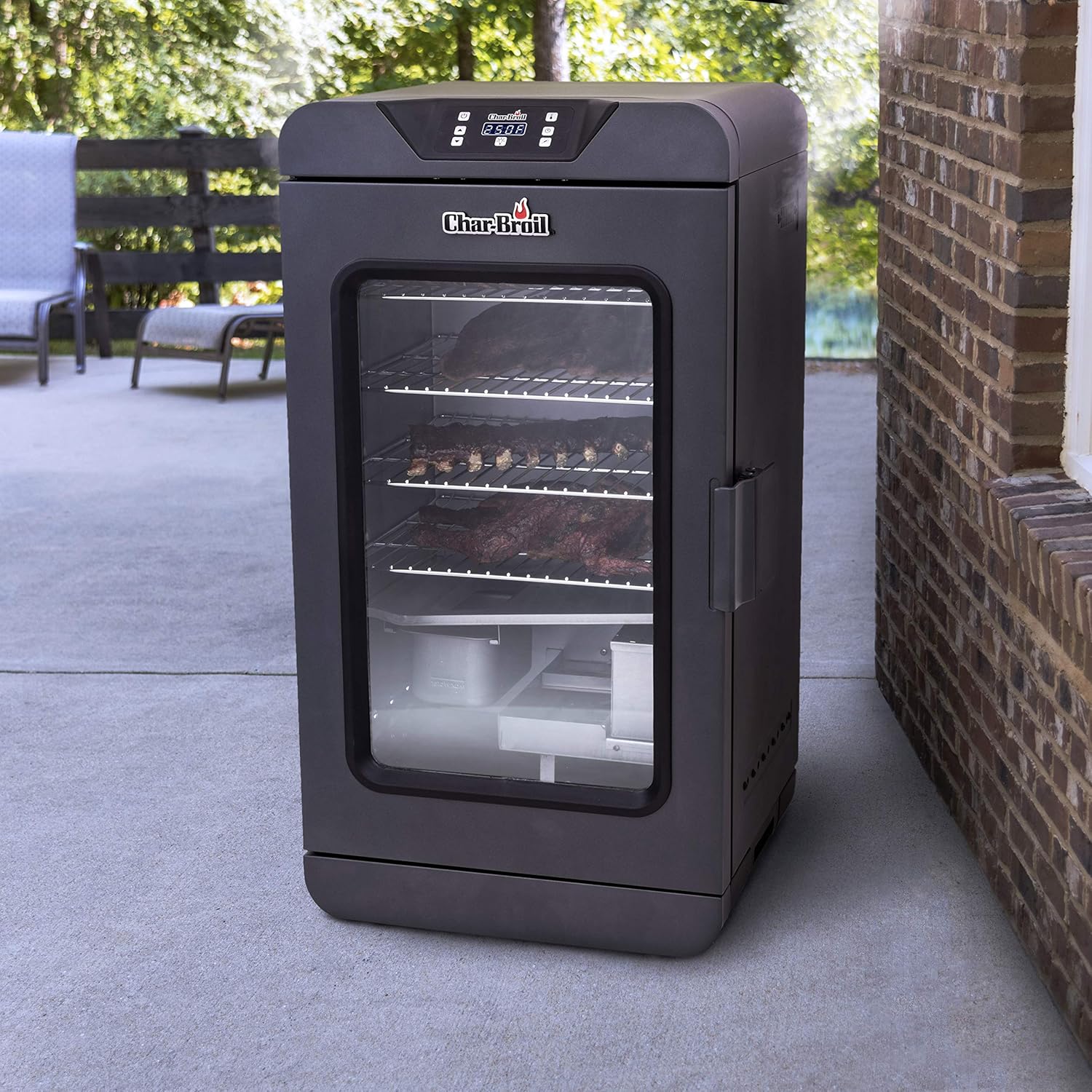 Elektrická udírna Char-Broil umístěná na terase vedle cihlové zdi, demonstrující venkovní použití.