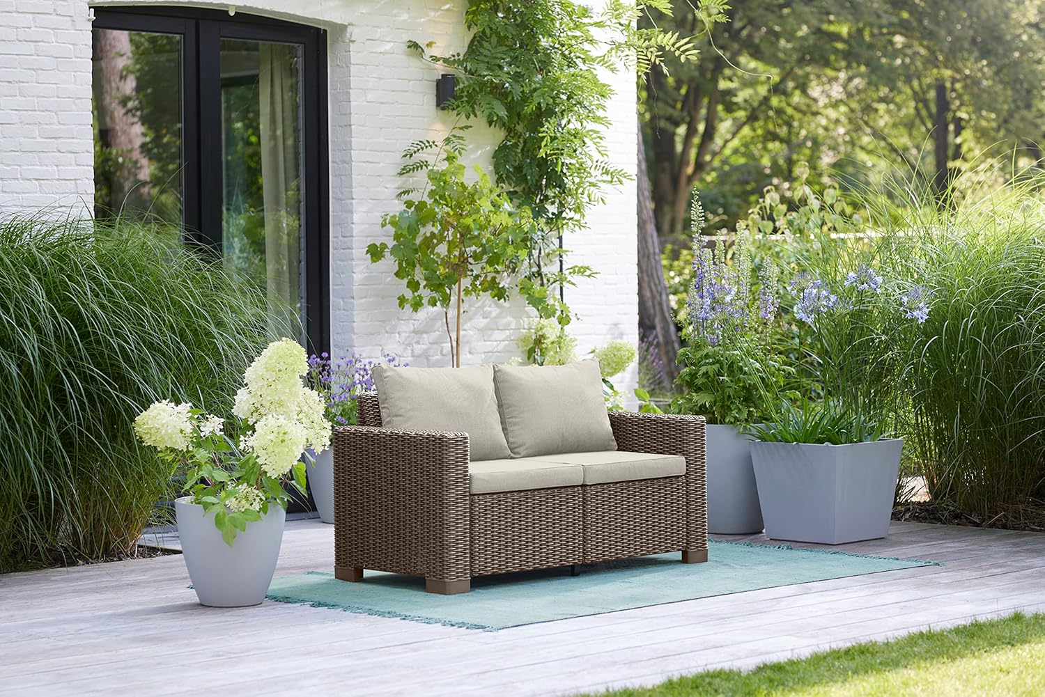 Keter California Garden Sofa placed on a patio with plants