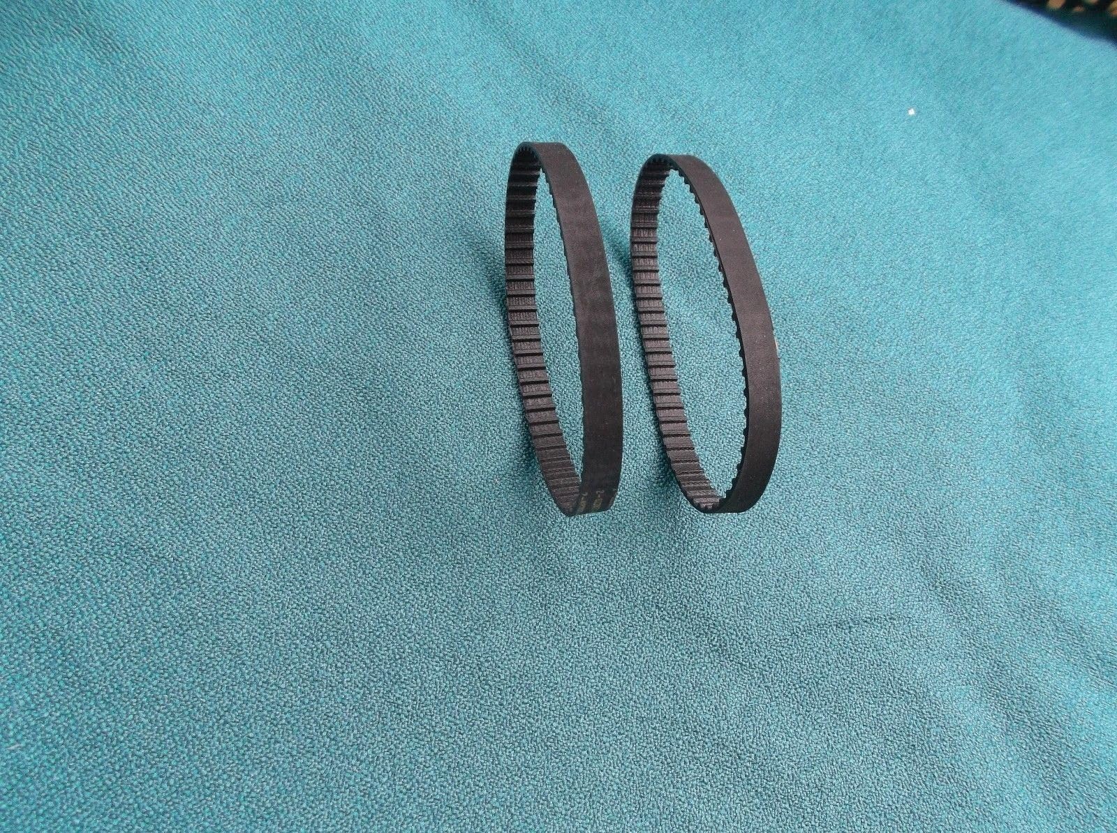 Two replacement drive belts for a band saw, coiled and shown against a white background.