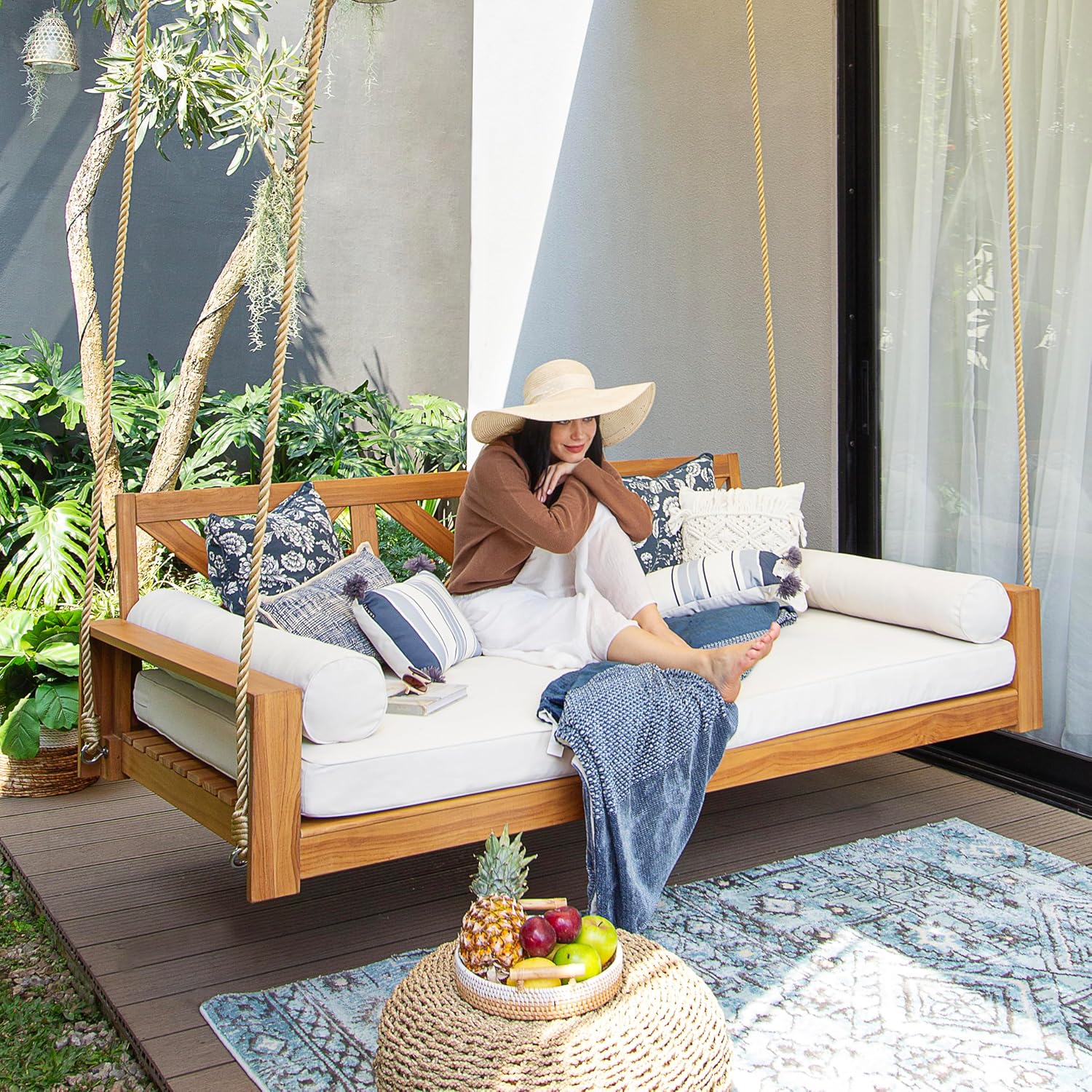 A person relaxing comfortably on the Logan Teak Wood Porch Swing Bed.