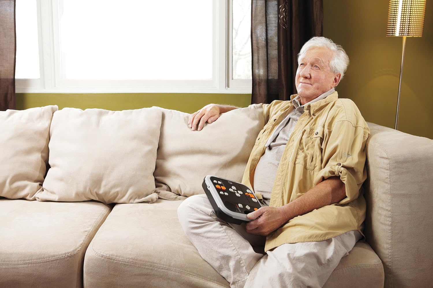 Elderly man comfortably using the Victor Reader Stratus4 M while sitting on a couch