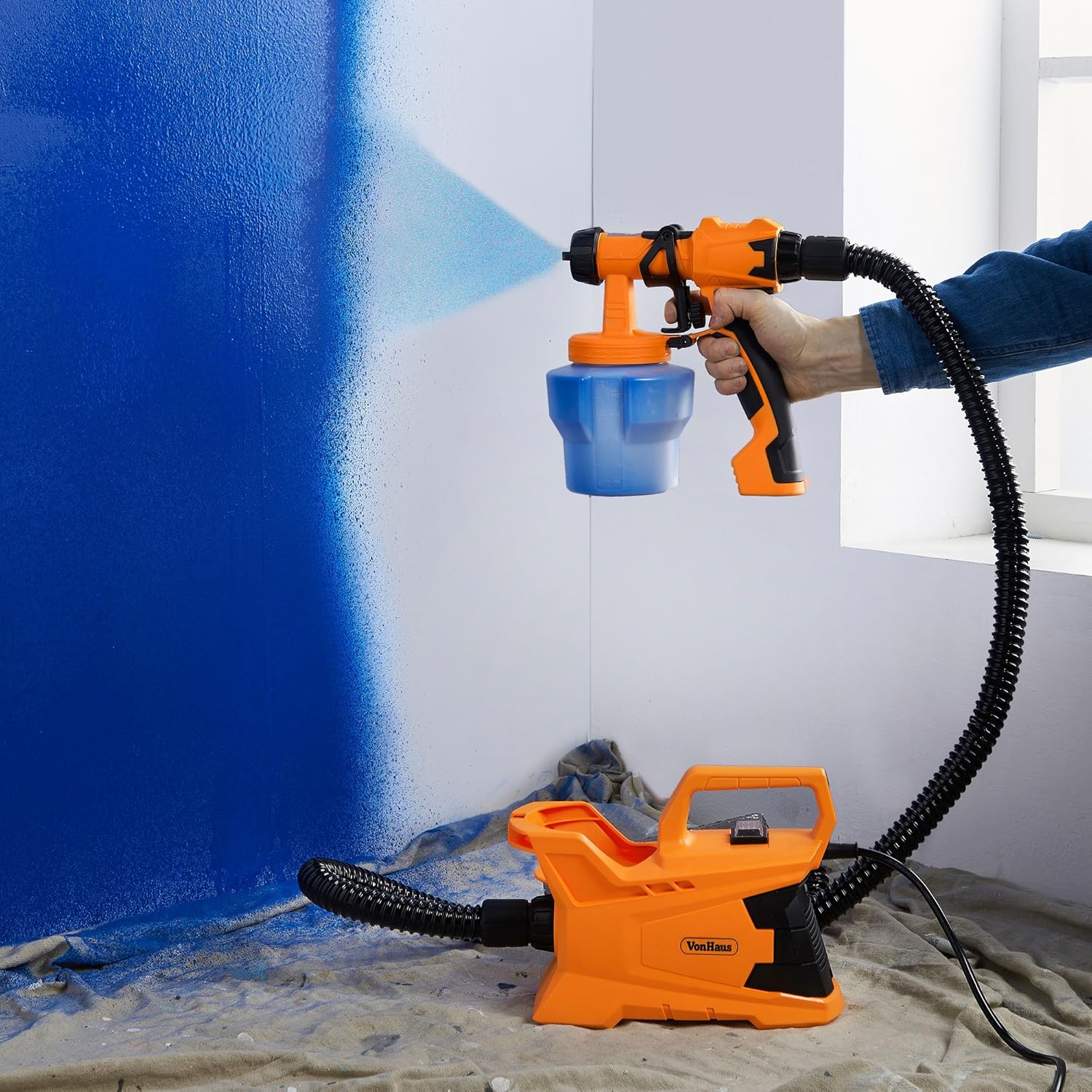 Person using VonHaus spray gun to paint an indoor wall