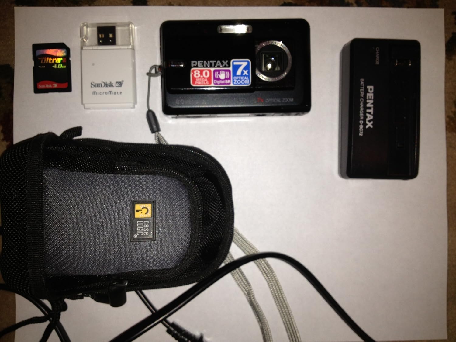 Pentax Optio Z10 camera and accessories including memory card, card reader, battery charger, and camera case.
