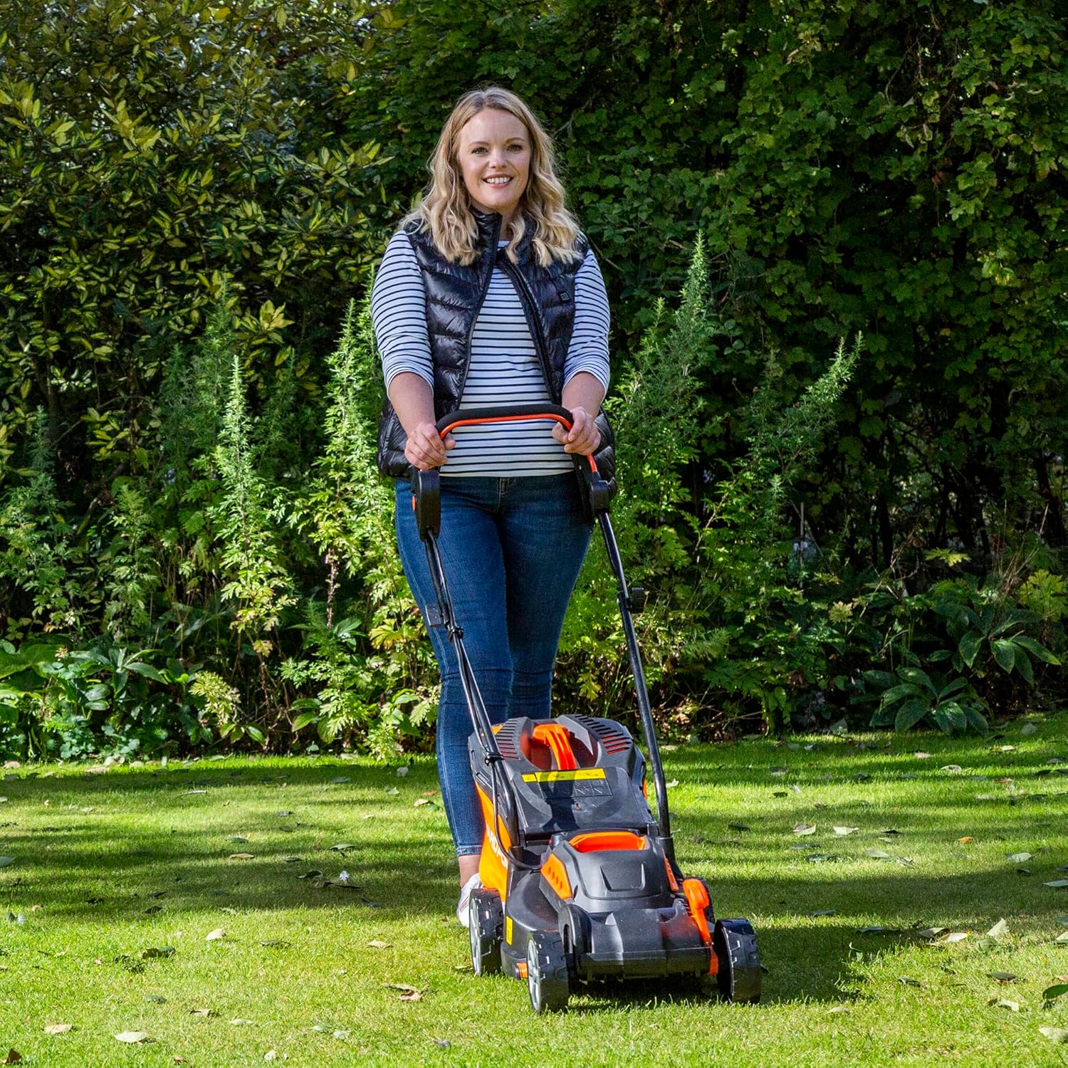 Woman operating Yard Force cordless lawnmower from the side