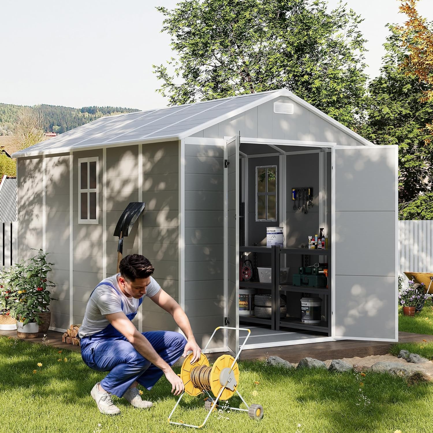 A person kneeling to operate a hose reel outside the UDPATIO 8x10 FT storage shed, with the shed doors open.