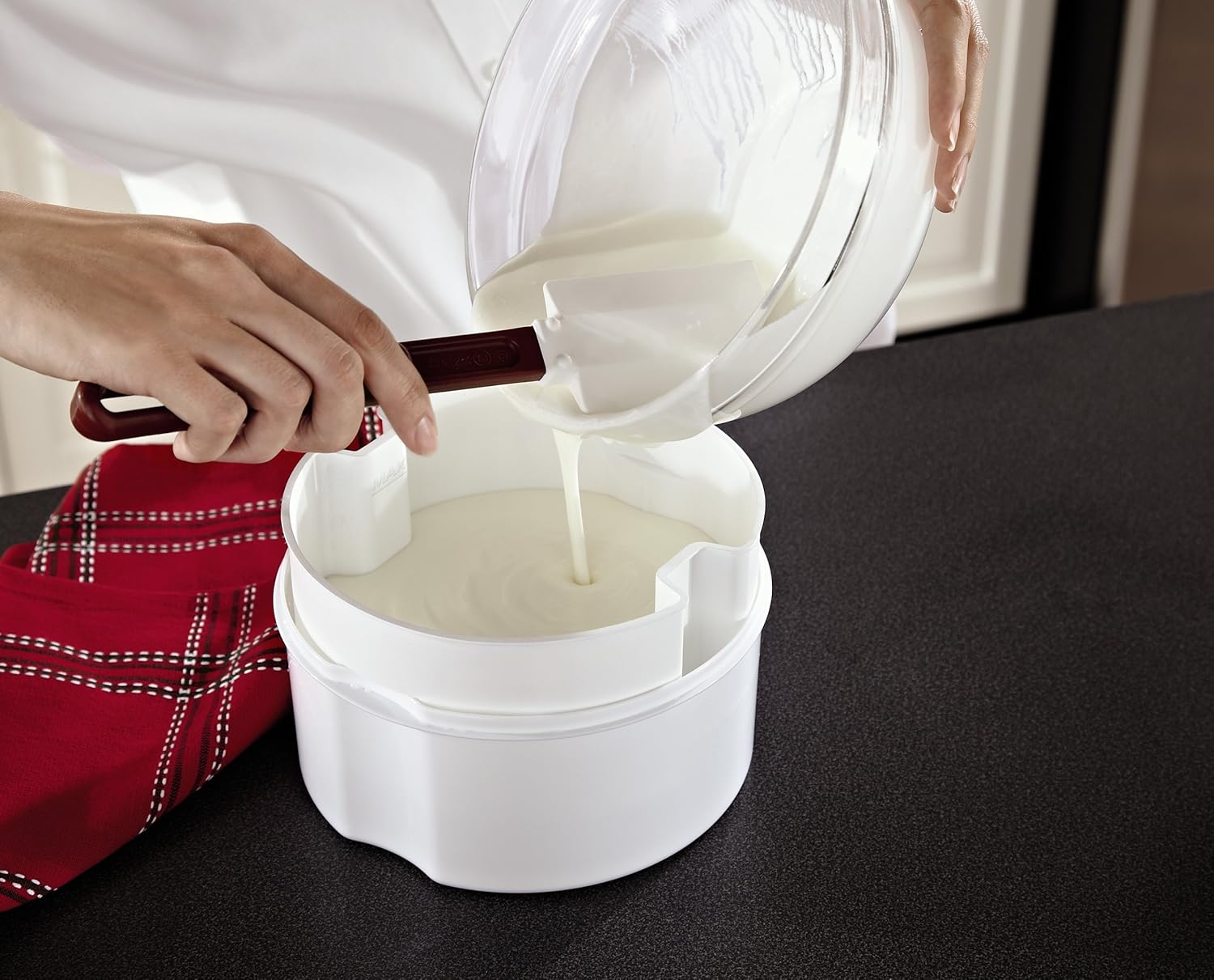 Person pouring yogurt into strainer in large container