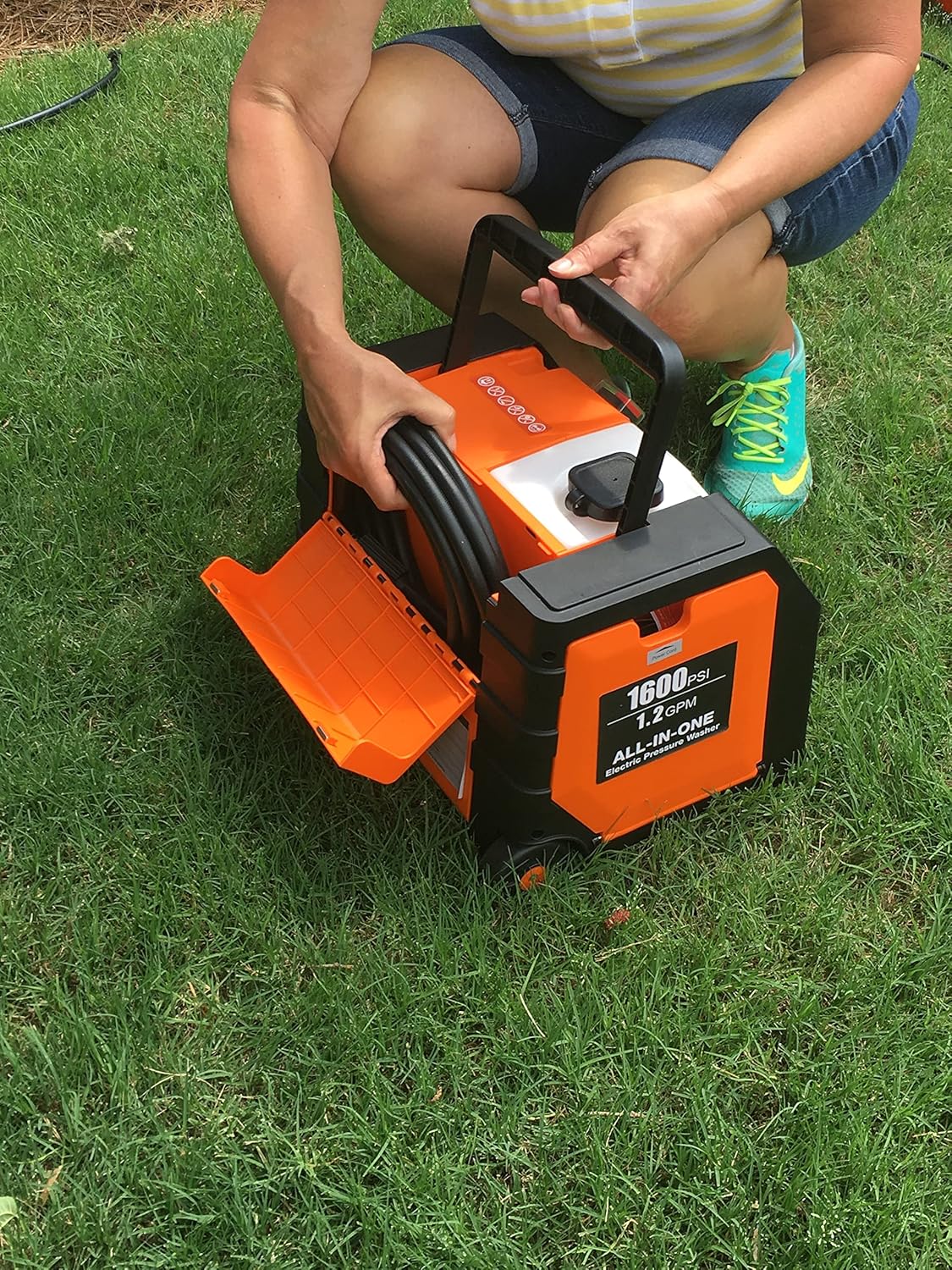 Person coiling pressure washer hose into storage