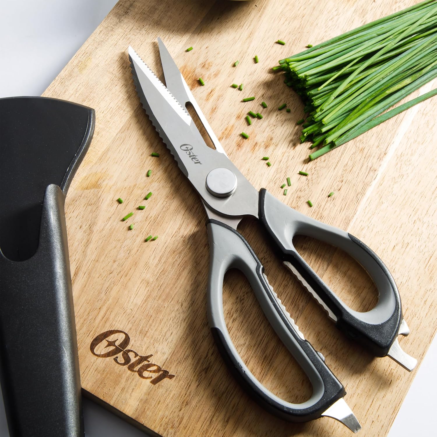 Oster Granger 9-inch Kitchen Shears on a wooden cutting board with chopped chives.