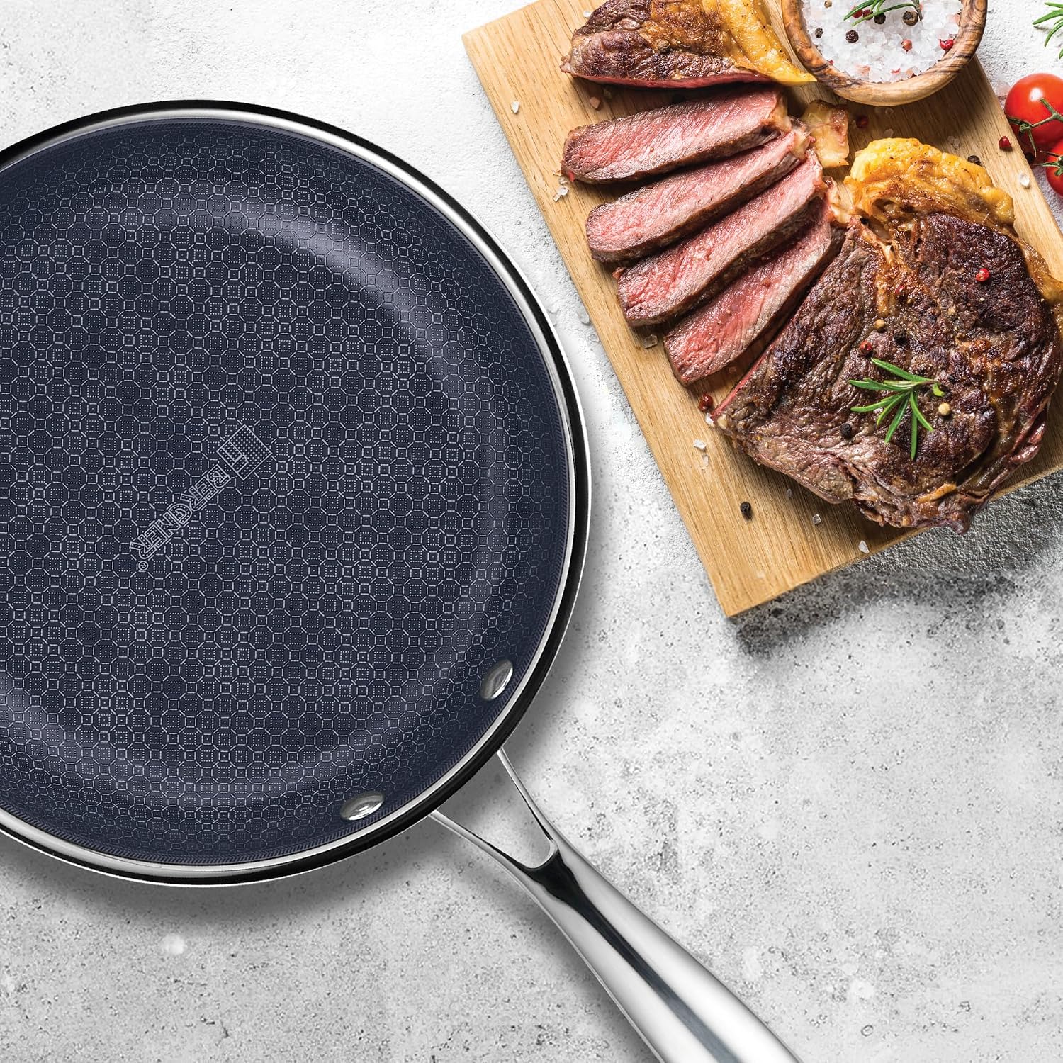 Overhead view of the BERGNER Steelblue frying pan next to a cutting board with sliced steak and fresh herbs.