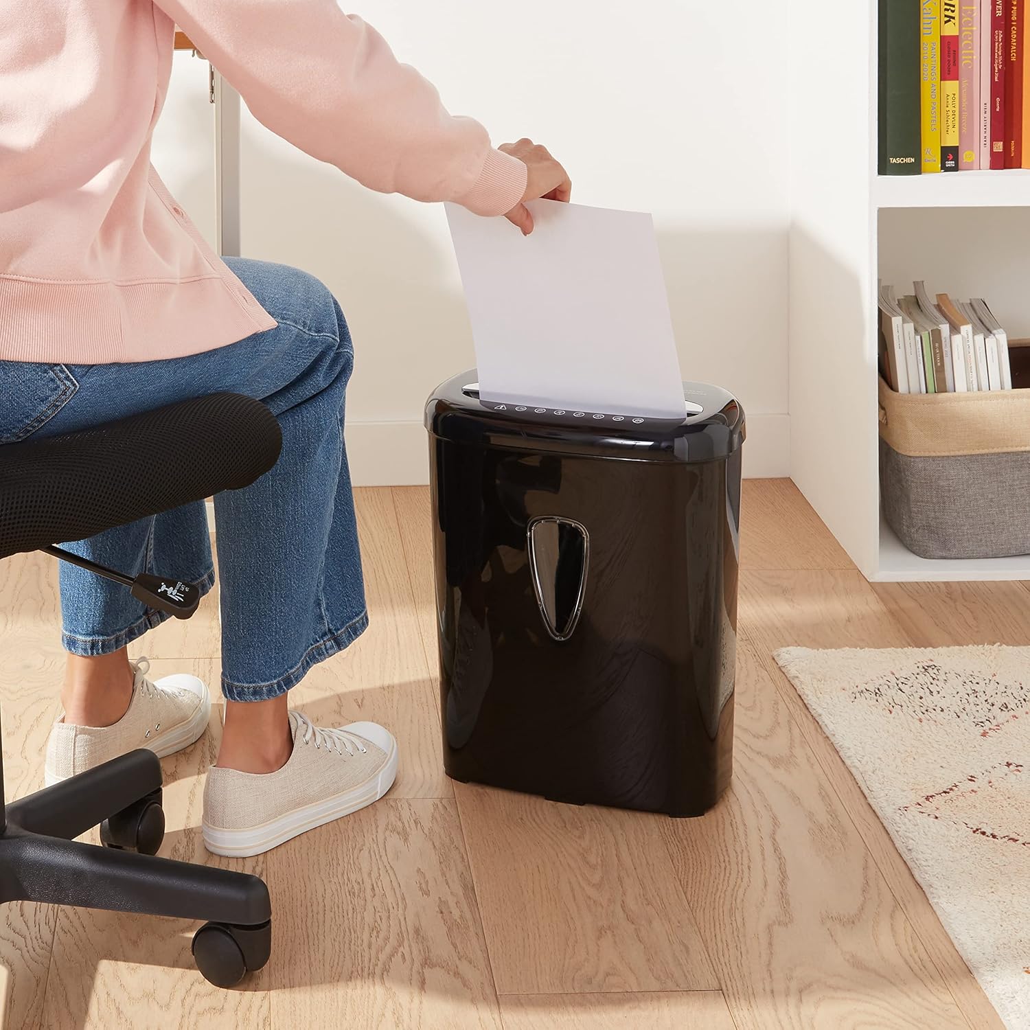 Person feeding paper into the Amazon Basics 6-Sheet Micro-Cut Shredder