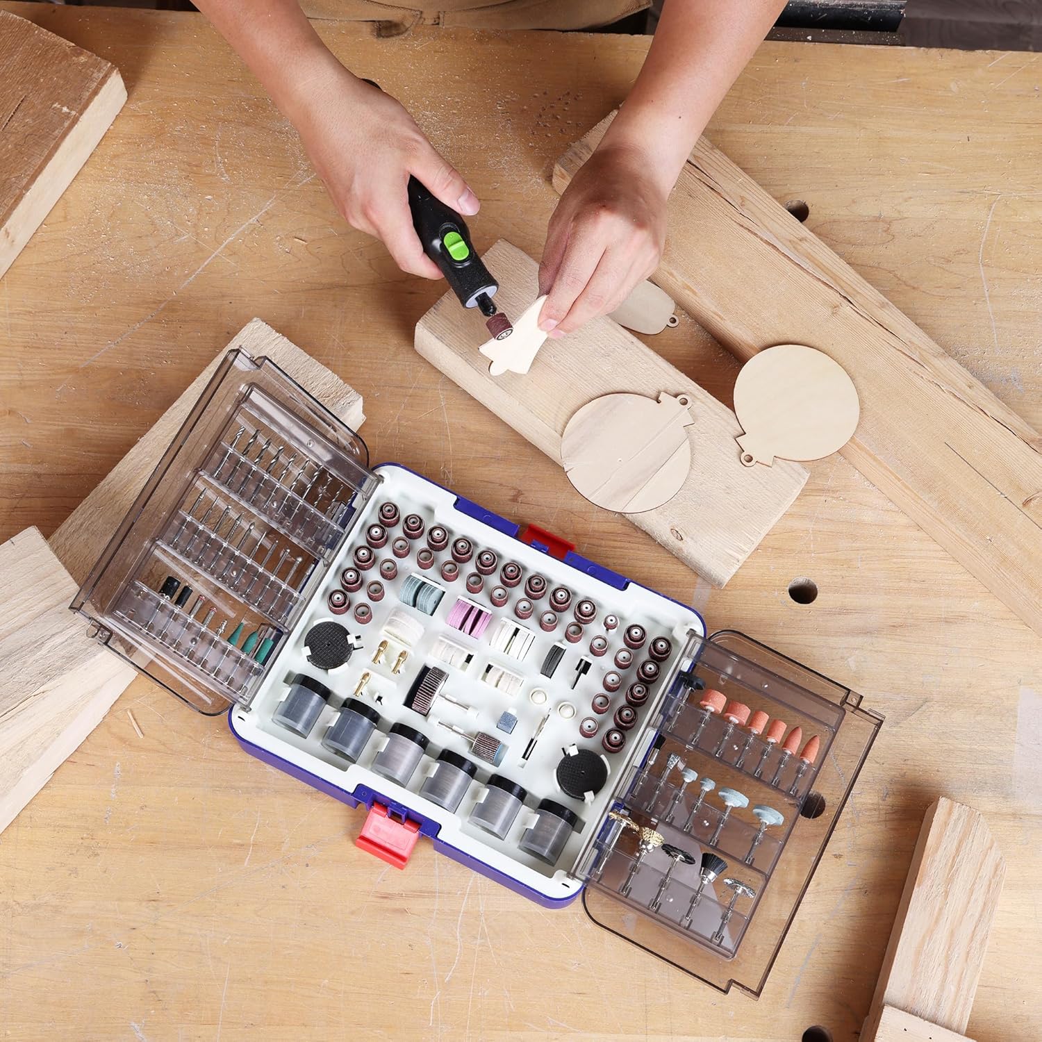 A person using a rotary tool with a sanding accessory, with the WORKPRO accessory kit open on a workbench.