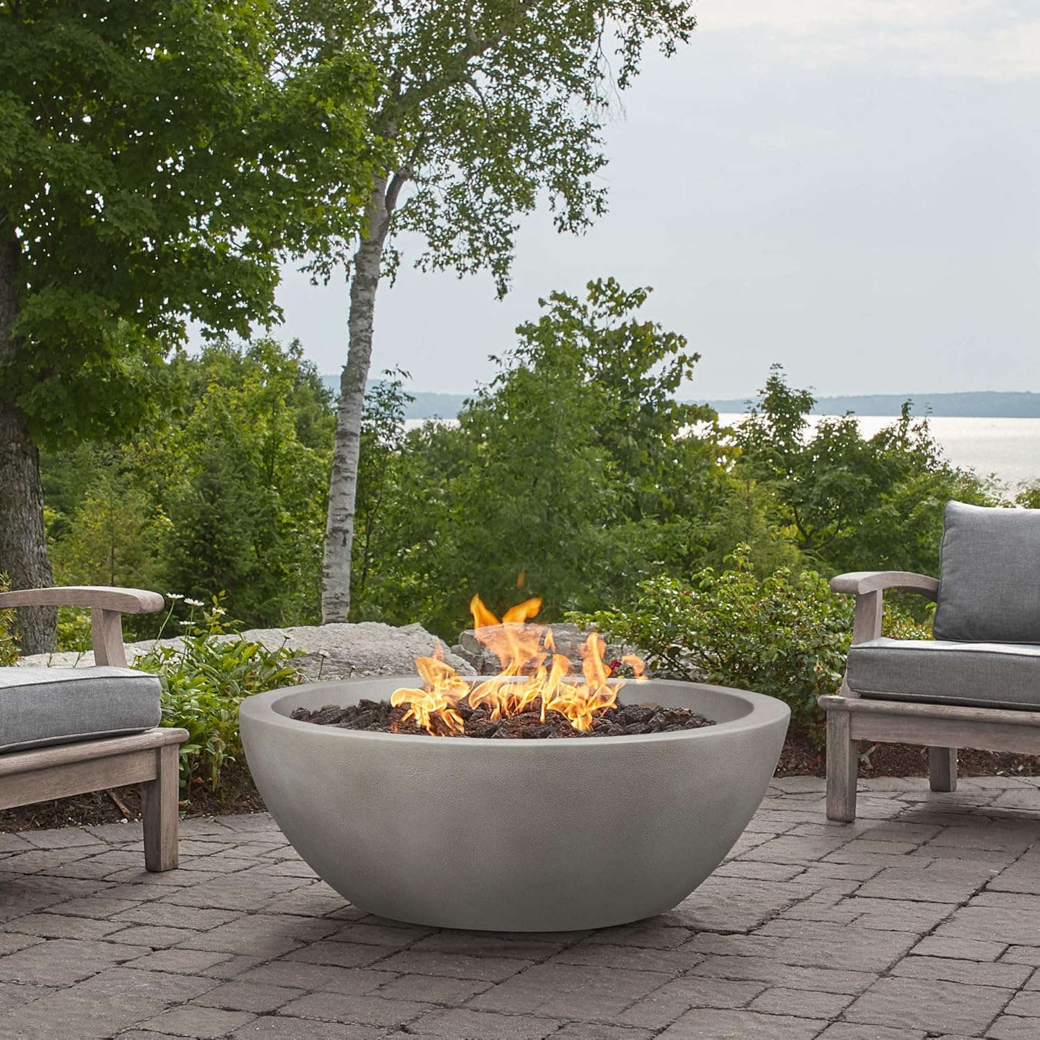 Real Flame Redding Fire Bowl placed on a patio with outdoor seating, overlooking a lake